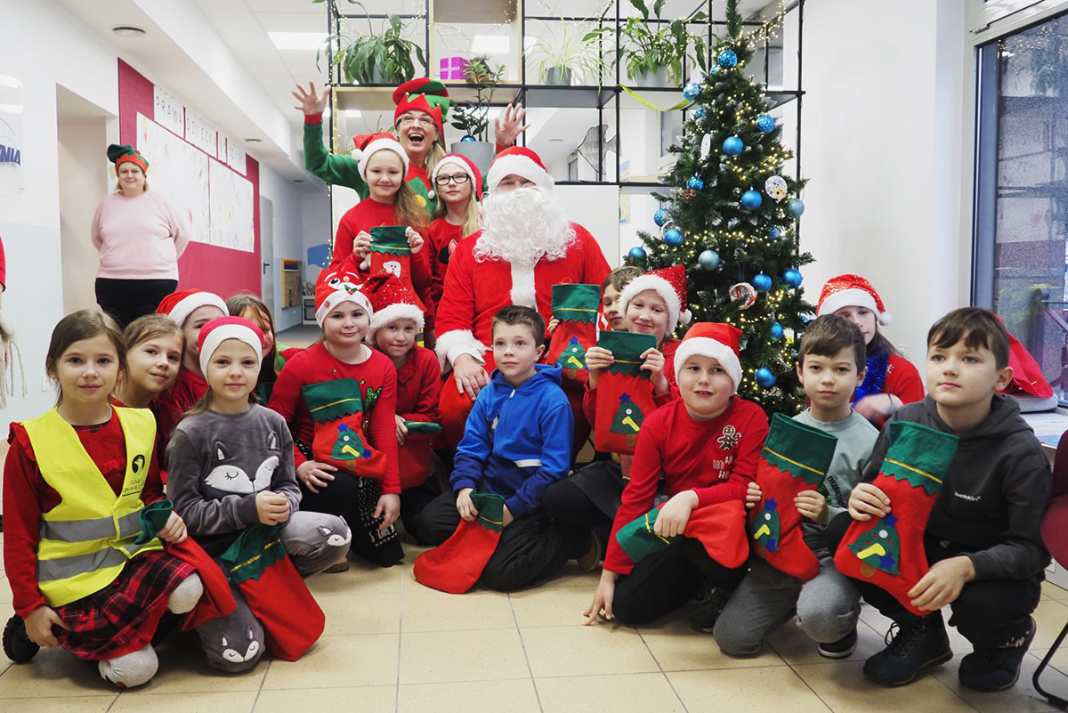 Dzieci w strojach Mikołajów z prezentami.