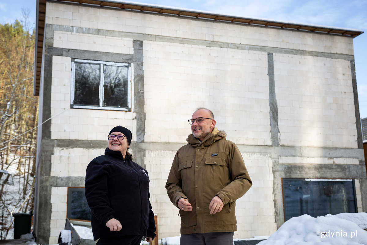 Uśmiechnięci kobieta i mężczyzna stoja przed budowanym budynkiem.