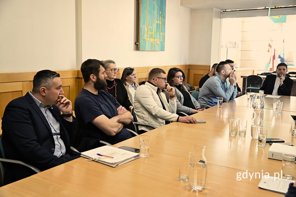 Grupa osób siedzących przy stole konferencyjnym