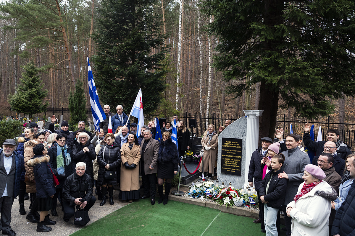 Tłum ludzi wokół pomnika na cmentarzu.