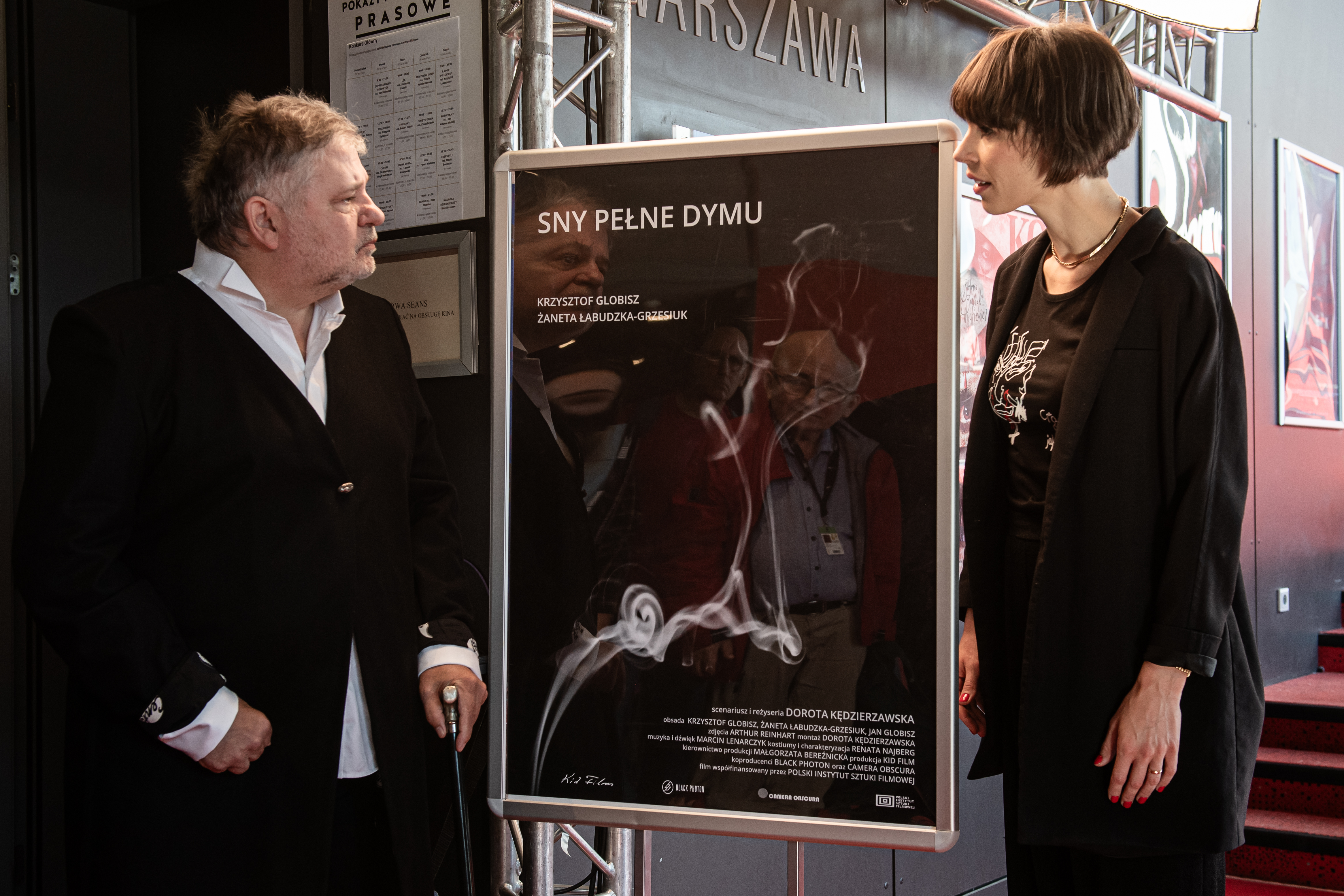 Krzysztof Globisz i Żaneta Łabudzka-Grzesiuk stoją obok plakatu filmowego na holu przed salą Warszawa w Gdyńśkim Centrum Filmowym