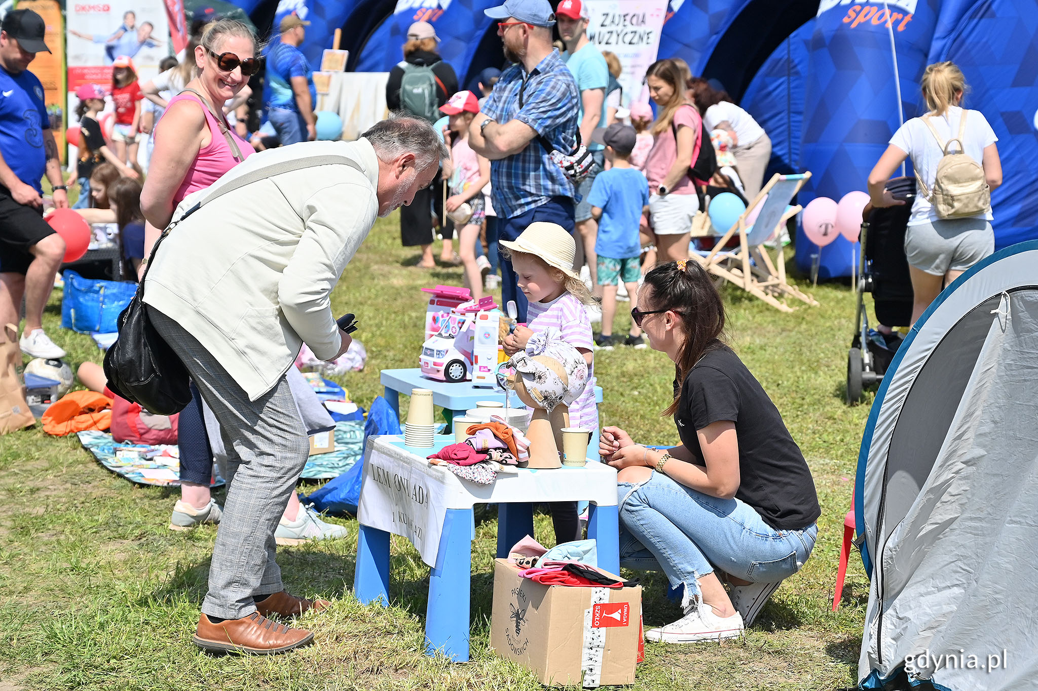 Prezydent Wojciech Szczurek na pikniku kupuje napój do dziewczynki