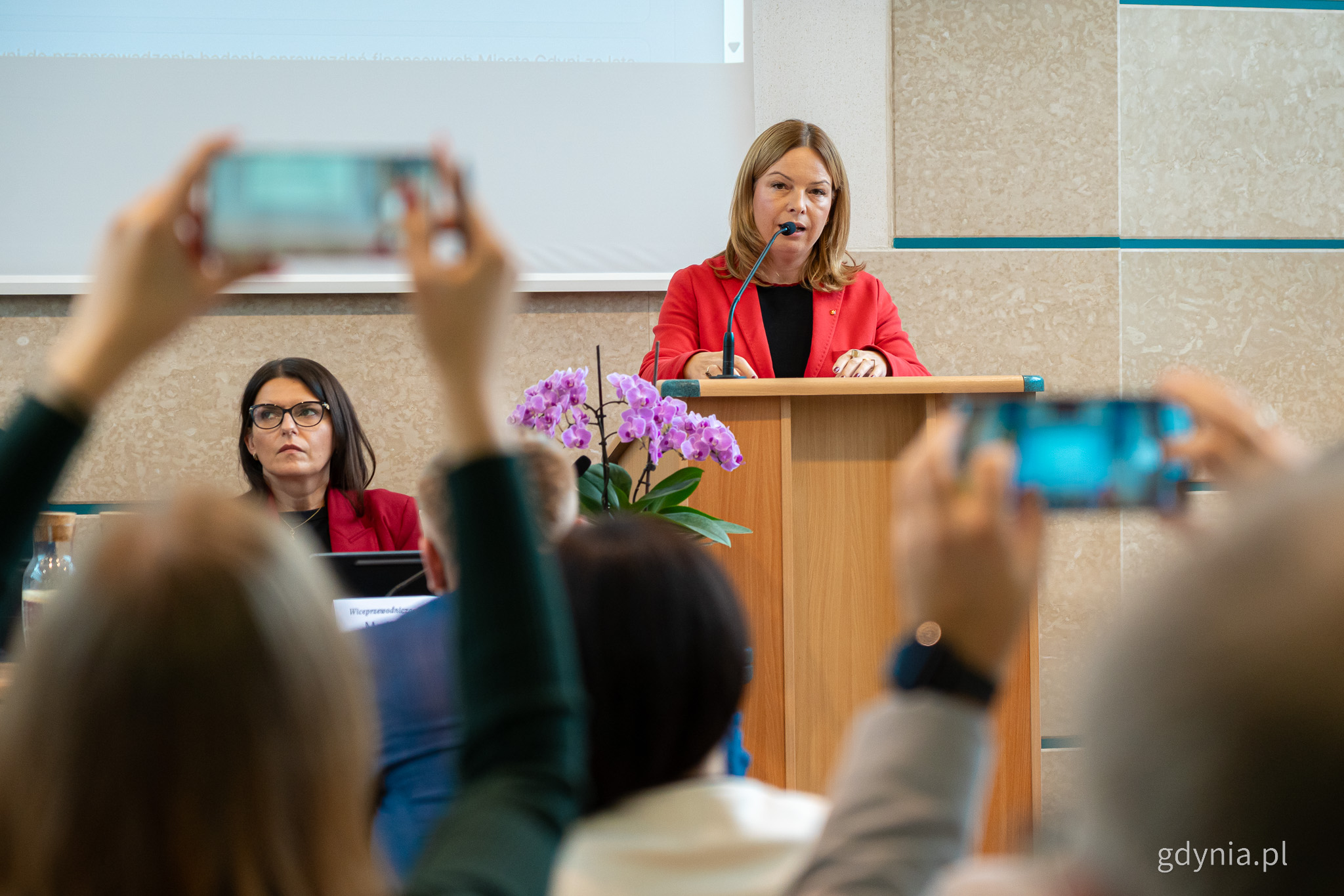 XXIII sesja Rady Miasta Gdyni. Przy mównicy Oktawia Gorzeńska, wiceprezydentka Gdyni, obok Mariola Śrubarczyk-Cichowska, wiceprzewodnicząca RMG