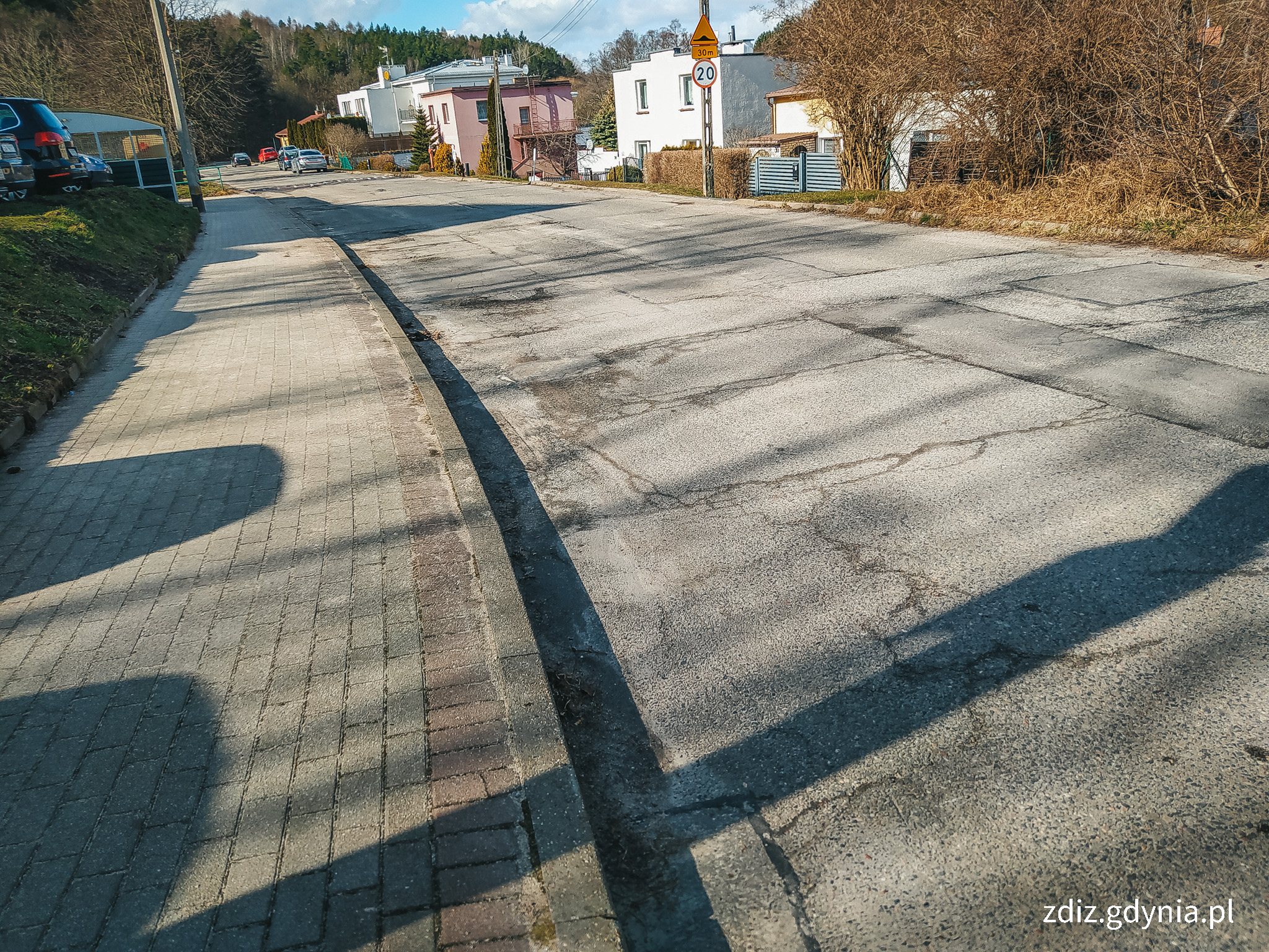 widoczny chodnik oraz ulica, słoneczny dzień, w tle widoczne osiedle