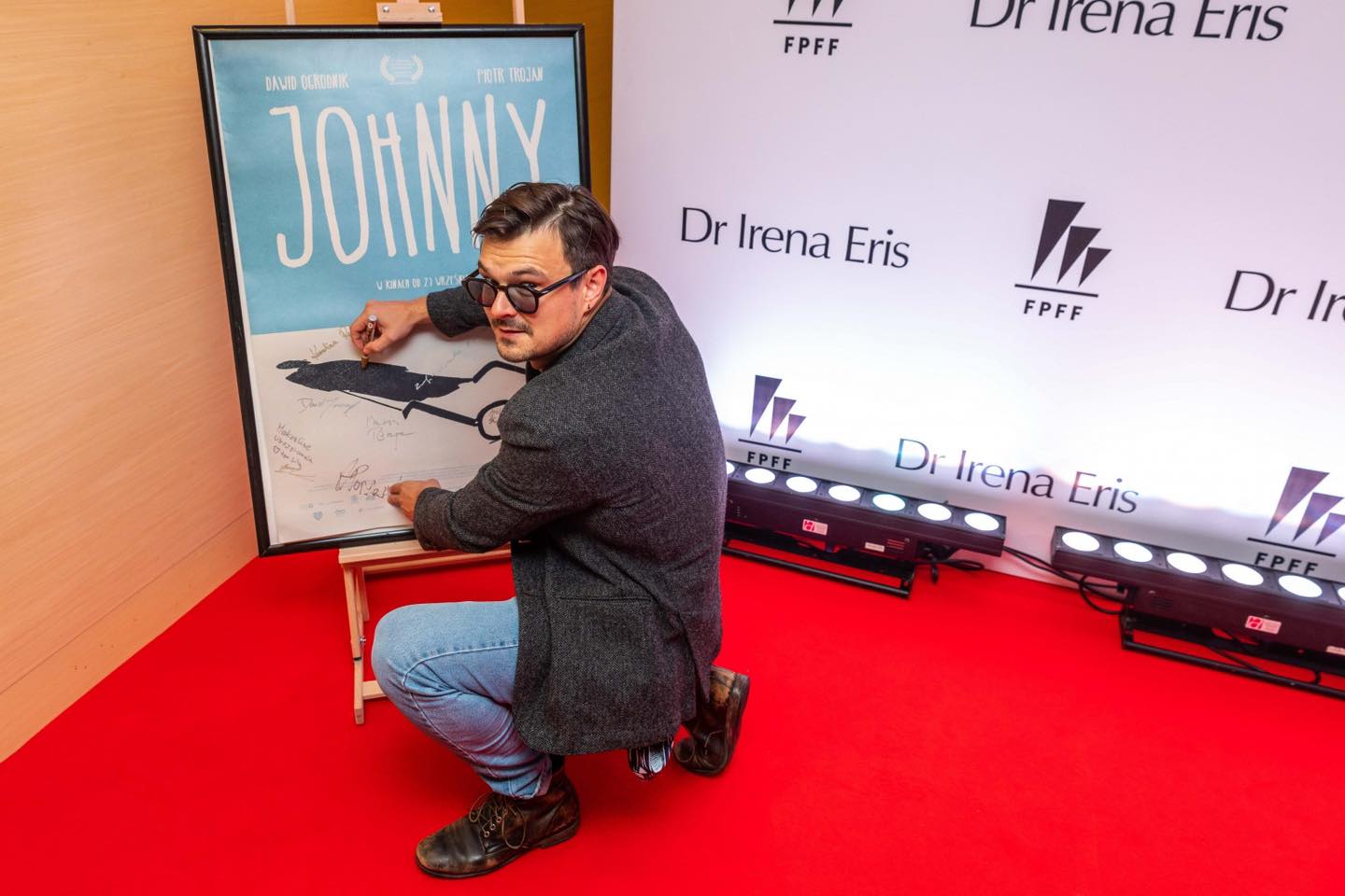 Dawid Ogrodnik podpisuje plakat promujący film „Johnny” // fot. materiały FPFF