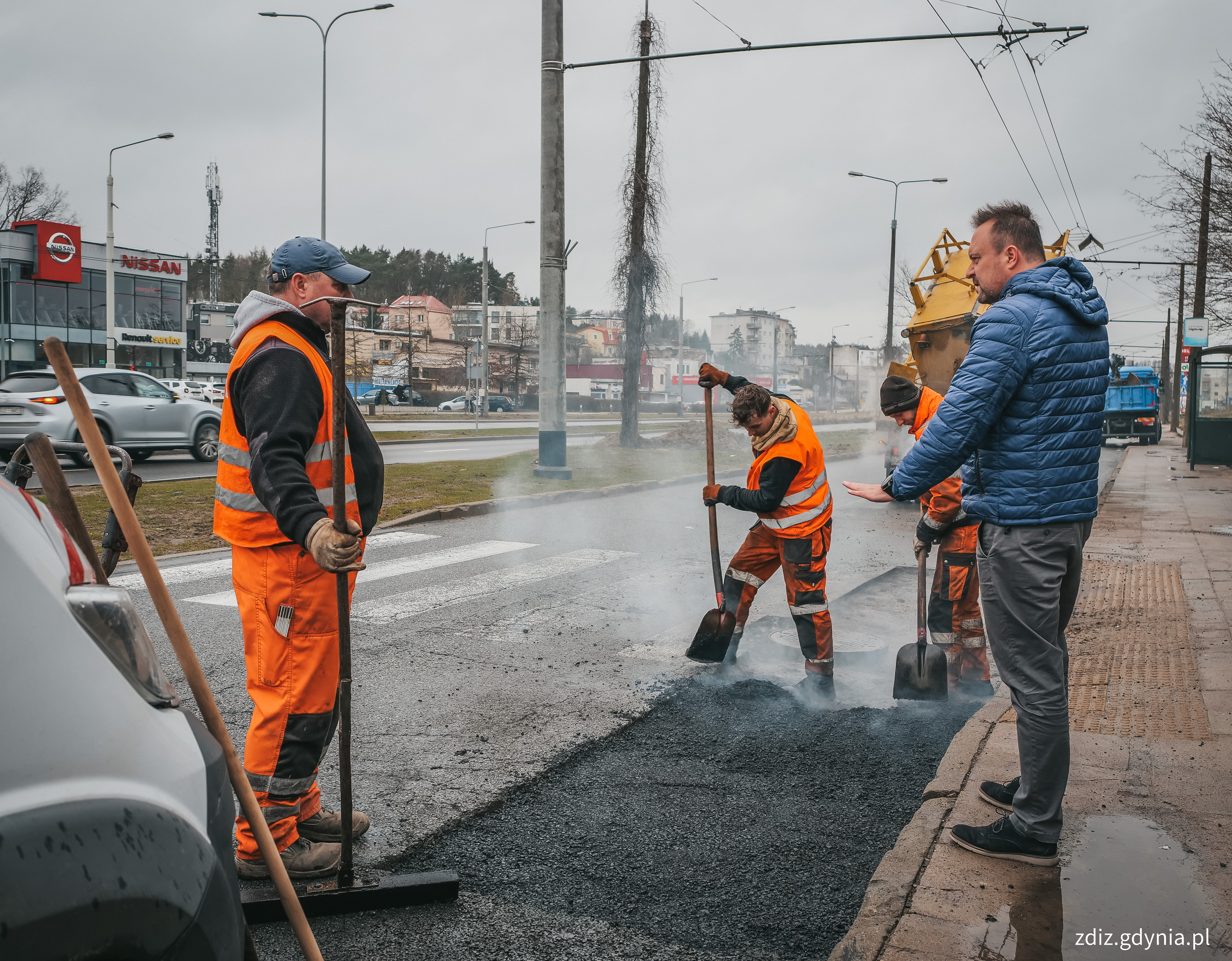 trwające roboty drogowe, widoczne osoby, remont nawierzchni 