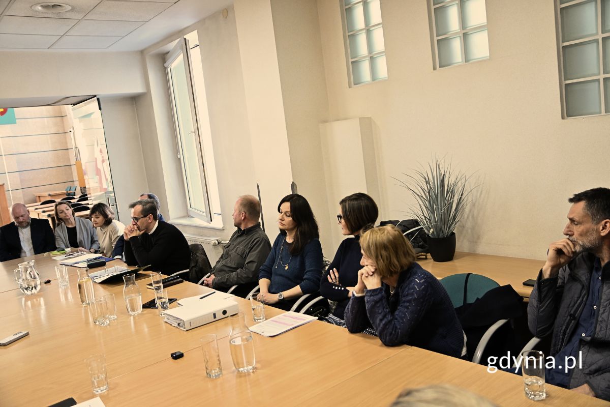 Grupa osób siedzących przy stole konferencyjnym