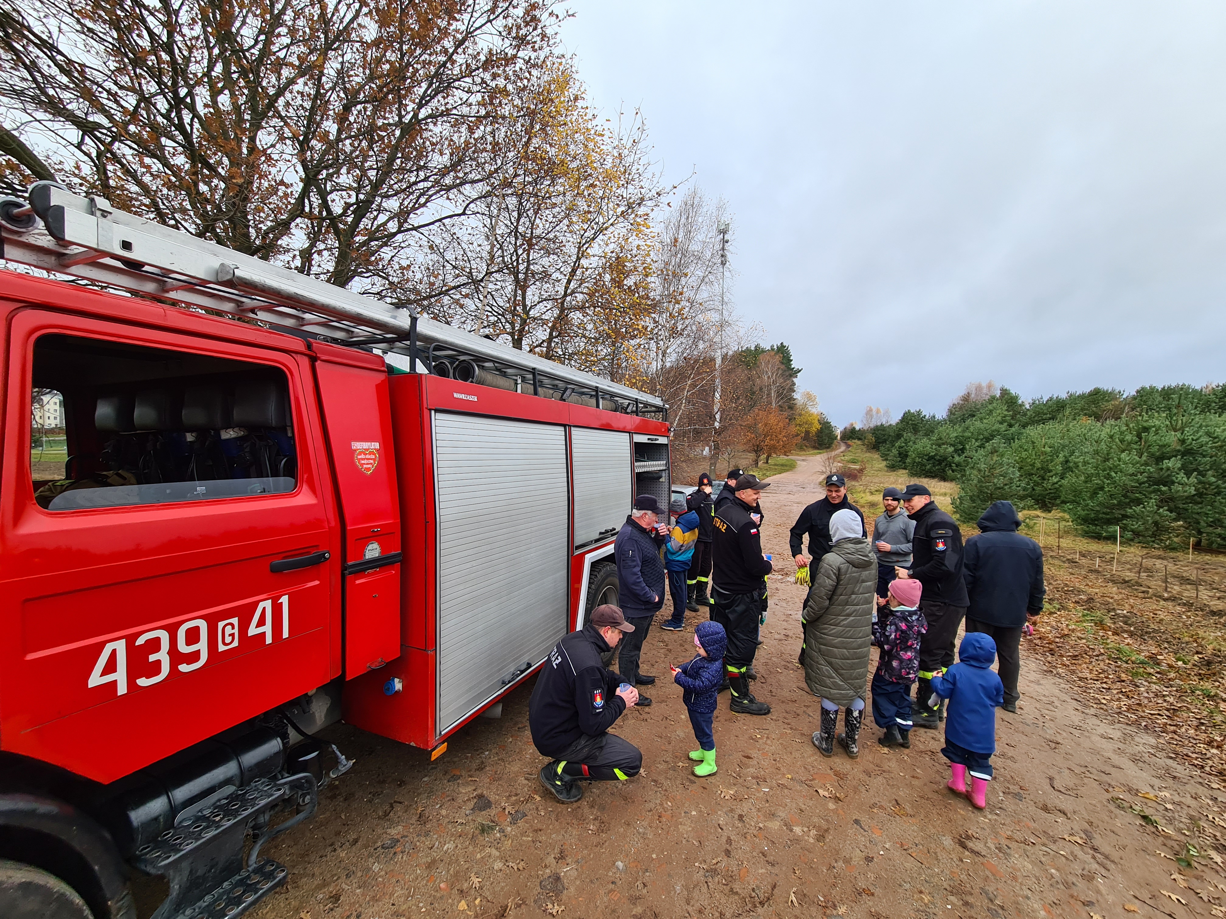 Na zdjęciu znajduje się wóz strażacki, a przy nim strażacy oraz mieszkańcy Wiczlina w leśnym anturażu