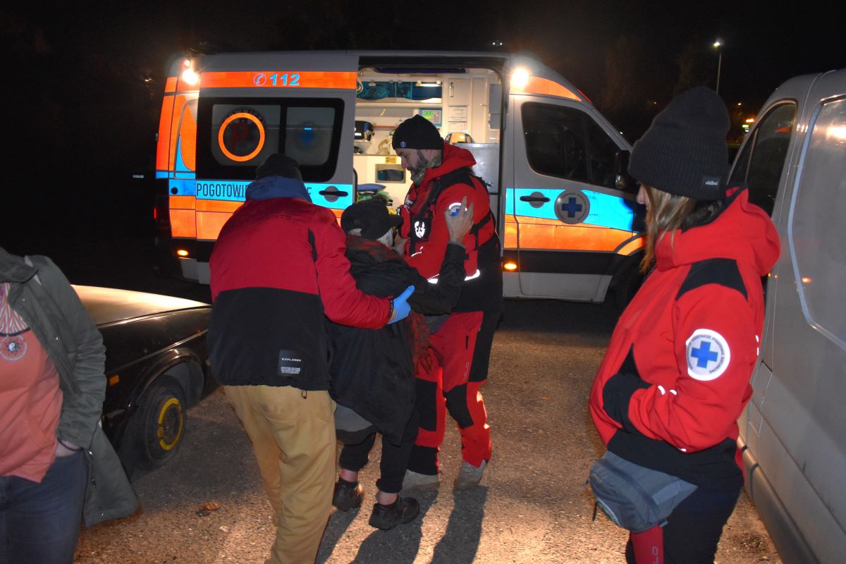 Na zdjęciu patrol streetworkerów i Poszukiwawczego Ochotniczego Pogotowia Ratunkowego, pomaga odnalezionej osobie bezdomnej dostać się do karetki. 