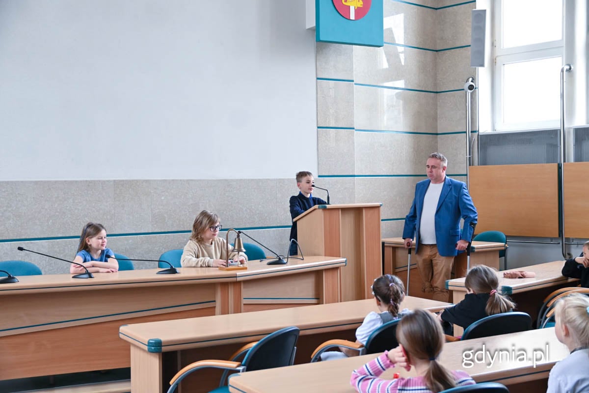 Uczniowie na sali obrad Urzędu Miasta Gdyni, biorące udział w symulowanej sesji na zdjęciu również radny Rady Miasta Gdyni Arkadiusz Dzierżyński.