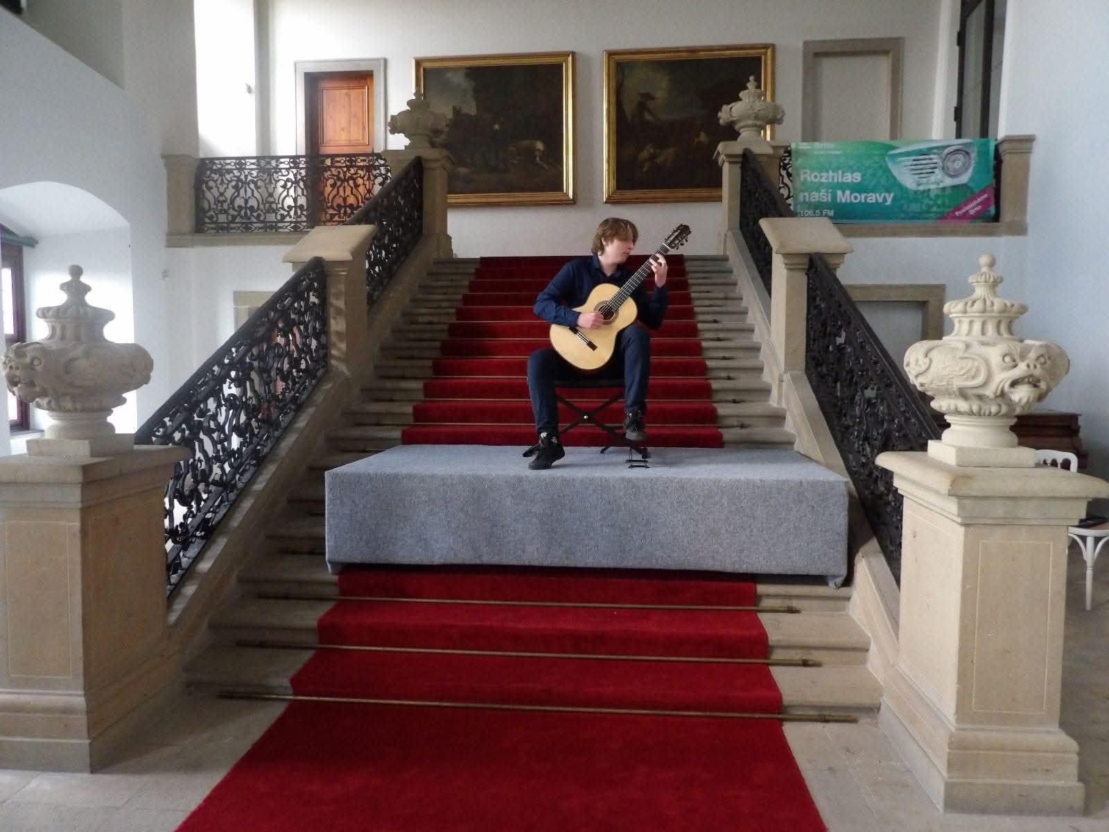 Tomasz Tamulewicz siedzi na schodach z gitarą