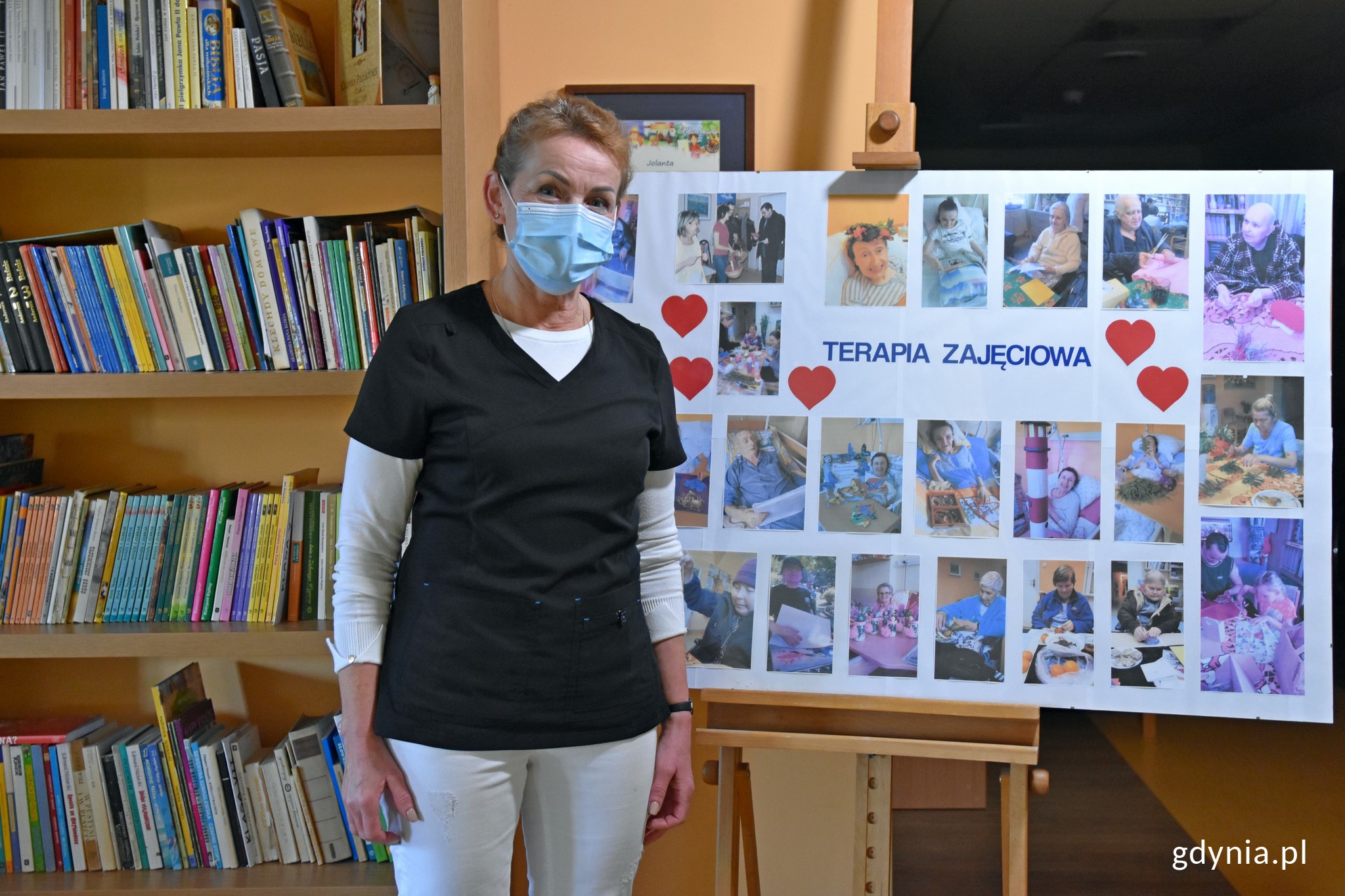 Grażyna Trowska - wolontariuszka w Hospicjum im. św. Wawrzyńca przy tablicy ze zdjęciami pacjentów // fot. Magdalena Czernek