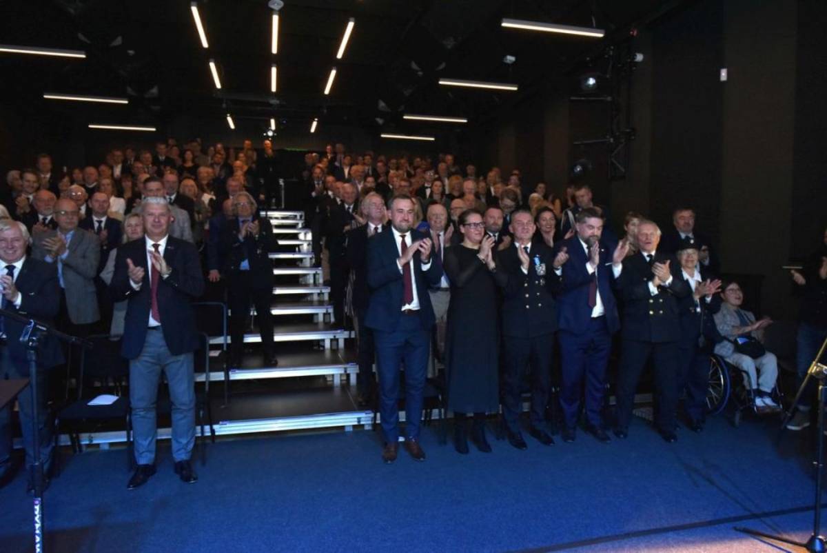 Elegancko ubrane osoby stojące i bijące brawo w dużej sali
