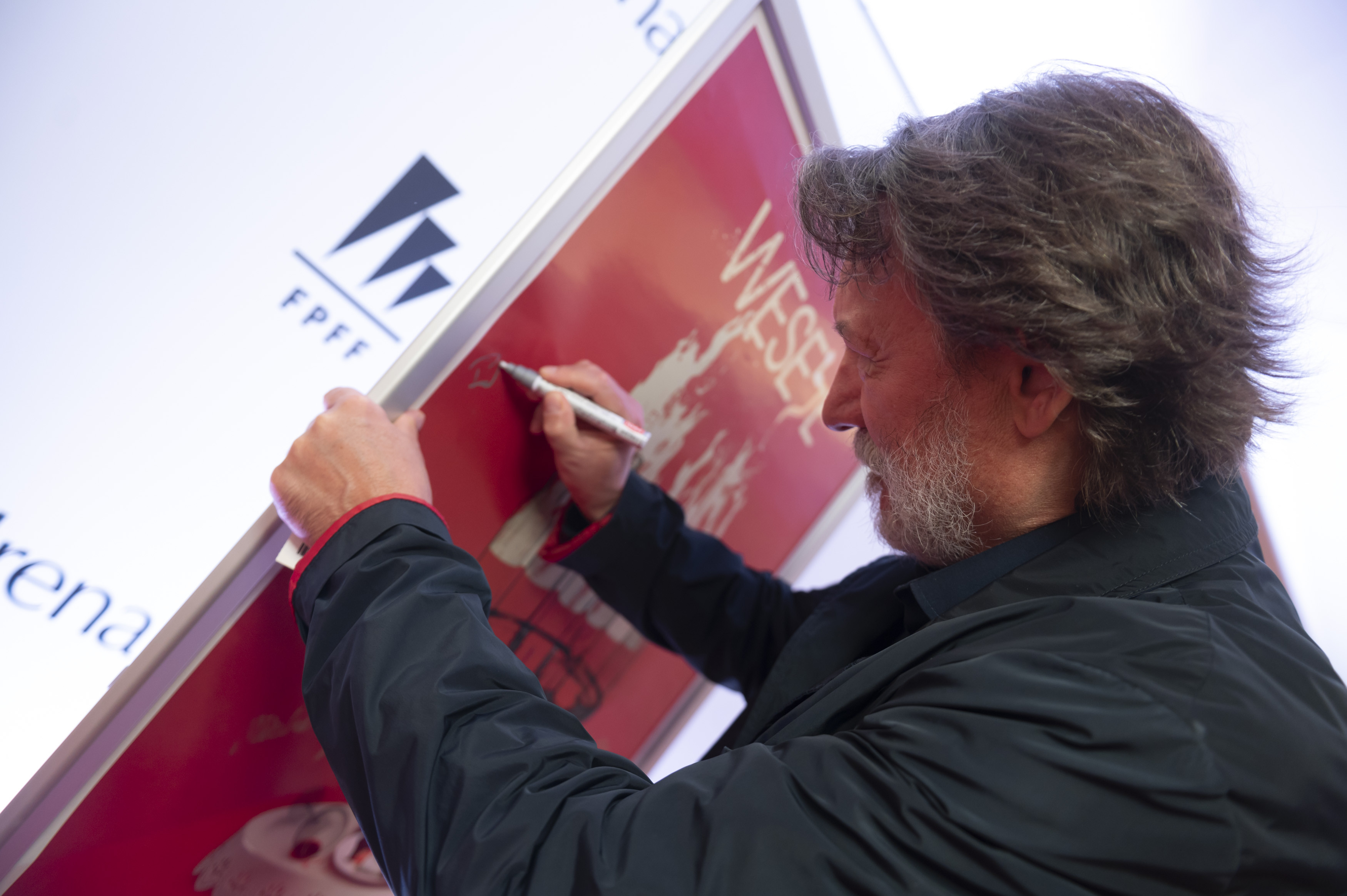 Robert Więckiewicz, jeden z najpopularniejszych polskich aktorów w trakcie składnia autografu na plakacie filmu „Wesele” Wojciecha Smarzowskiego, fot. mat. prasowe FPFF