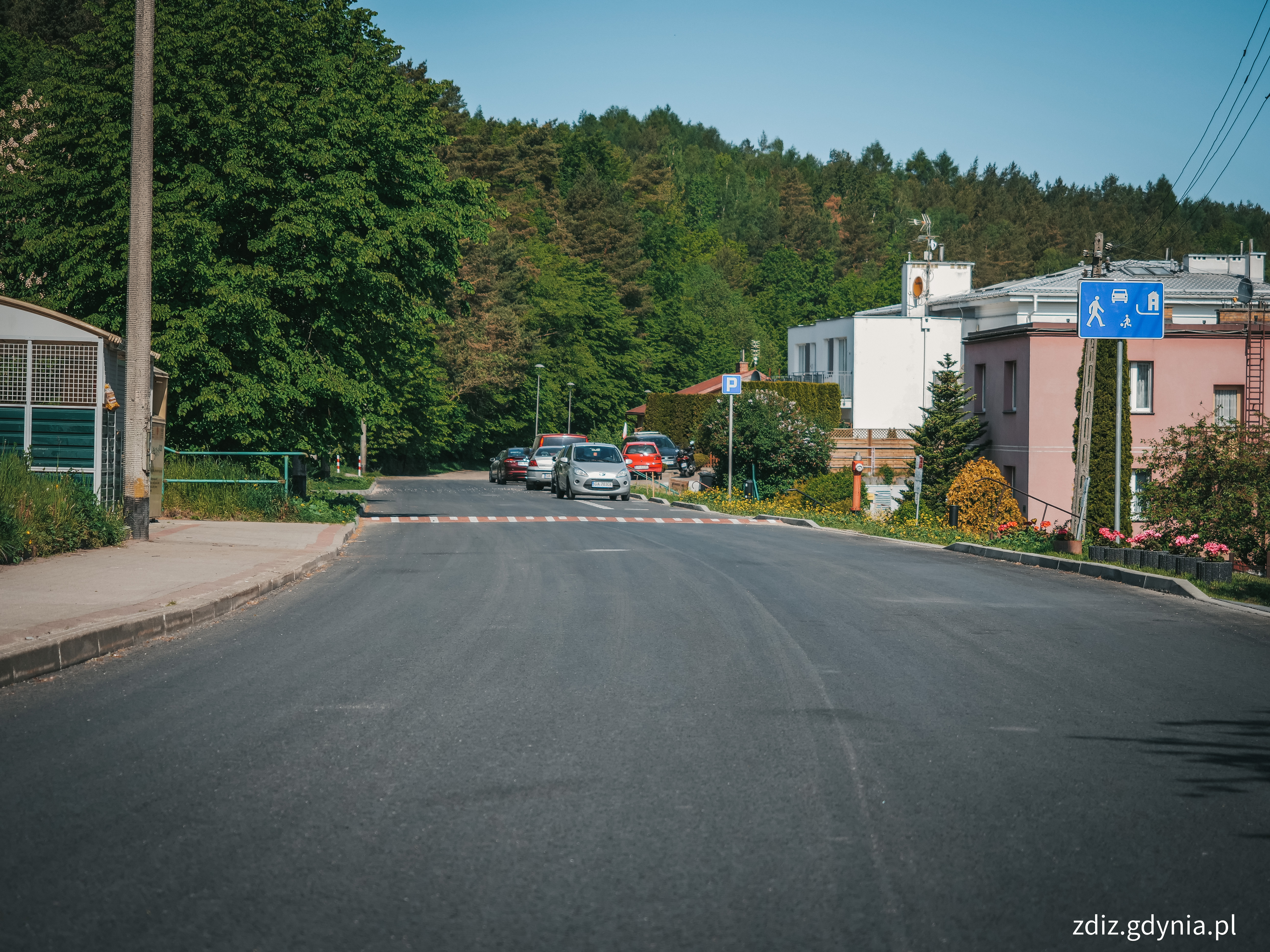 ulica, widoczny nowy asfalt oraz znak strefy zamieszkania