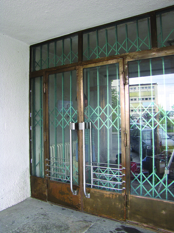 Drzwi bocznego wejścia do Sądu Rejonowego przy placu Konstytucji 5. Jedyny w Gdyni przykład metalowych drzwi z lat 30. XX w., w których konstrukcja w kolorze mosiądzu została zestawiona z pochwytami z kolorze srebrnym.