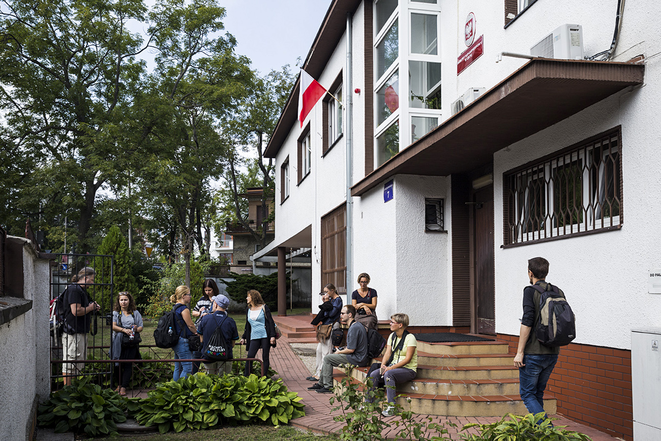 Ludzie na spacerze oglądają modernistyczną willę.