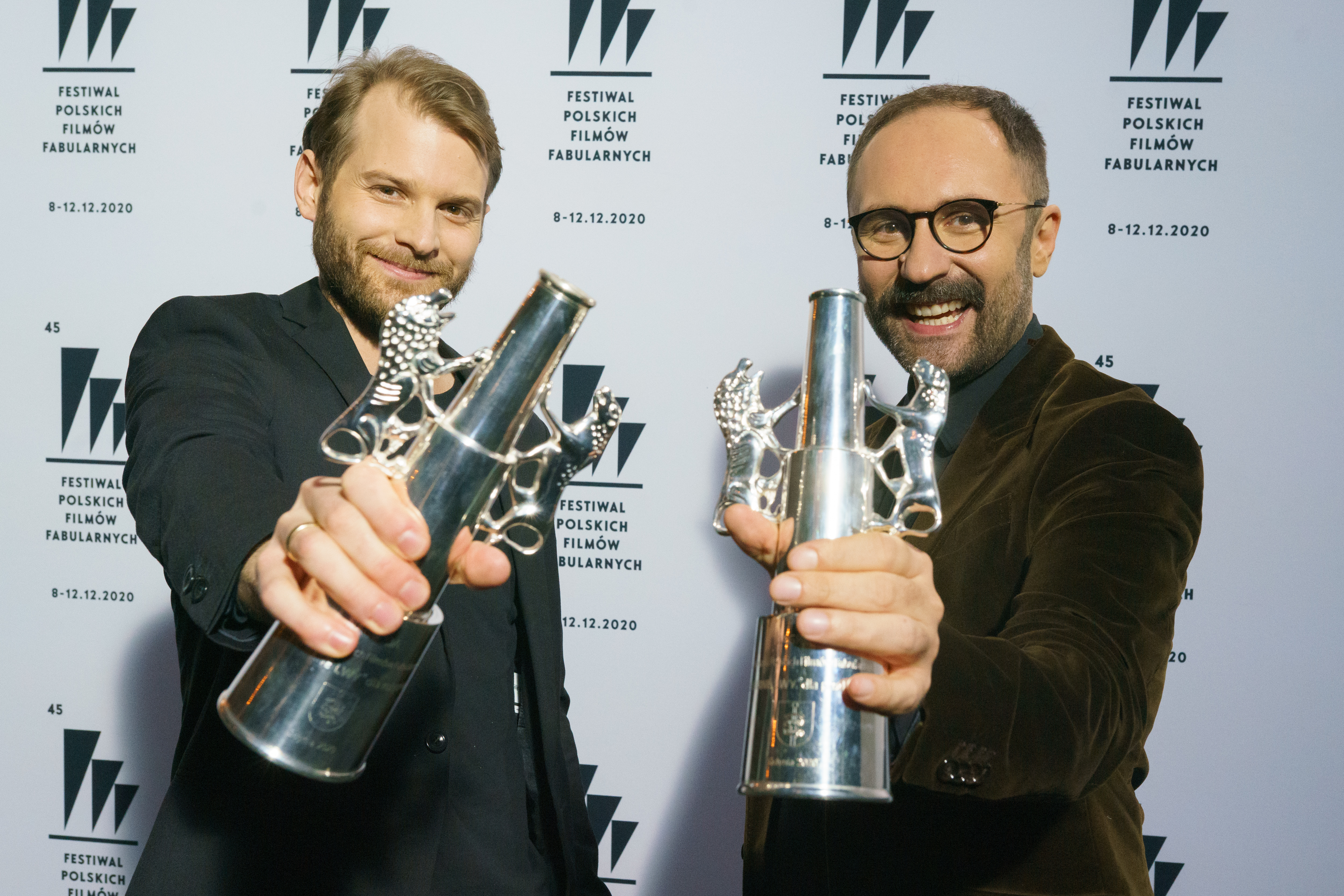 Magnus von Horn i Mariusz Włodarski ze statuetkami Srebrnych Lwów w rękach stoją na tle białej ścianki z czarnymi miniaturkami logo festiwali // fot. Anna Rezulak