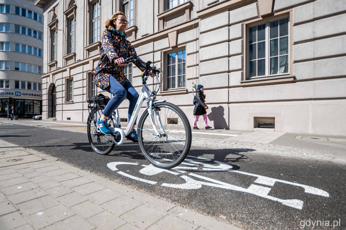 Na zdjęciu widzimy kobietę jadącą na rowerze elektrycznym