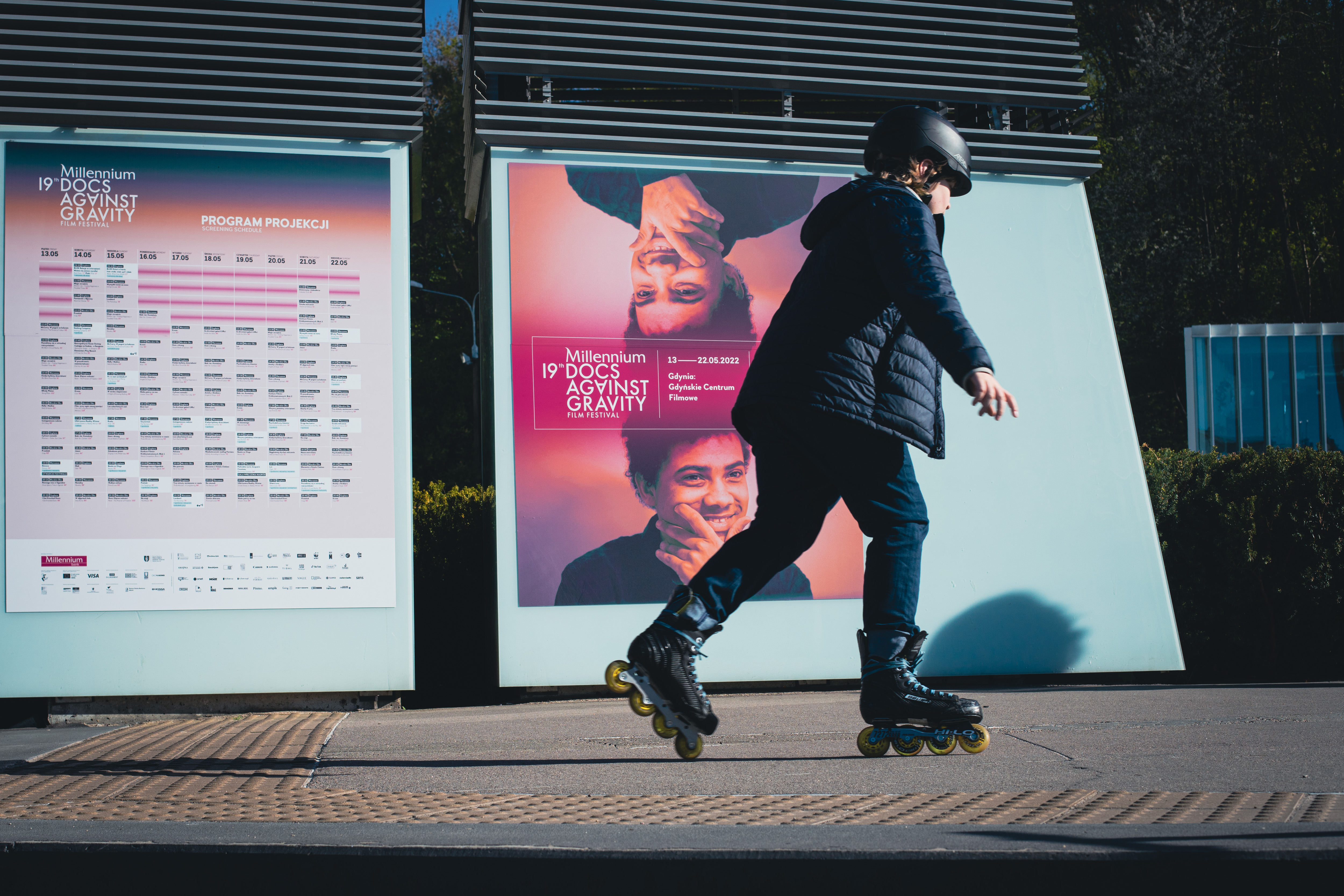 Plakat 19. edycji MDAG w centrum miasta i przejeżdżający chłopiec na rolkach // fot. Anna Rezulak