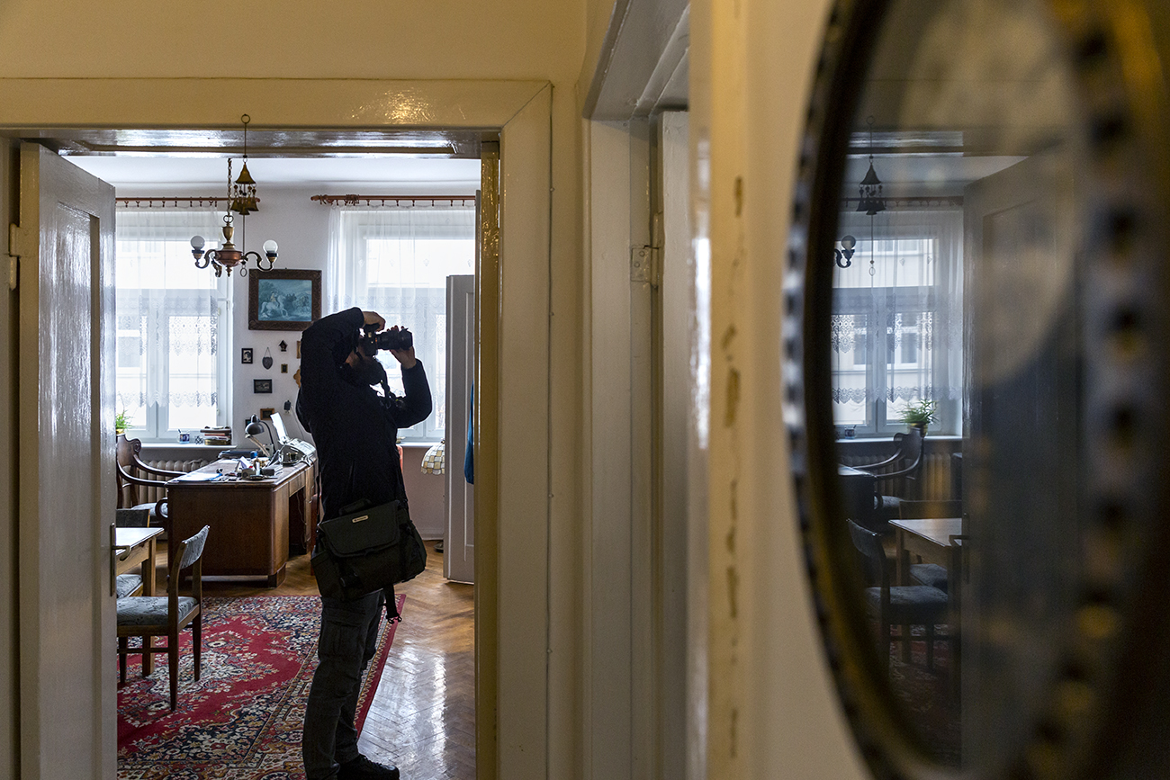 Mężczyzna fotografuje wnętrze starego mieszkania z zachowanymi elementami wystroju sprzed lat.