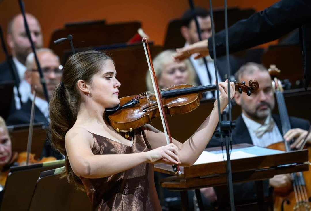 Zoja Syguda gra na skrzypcach podczas występu z orkiestrą