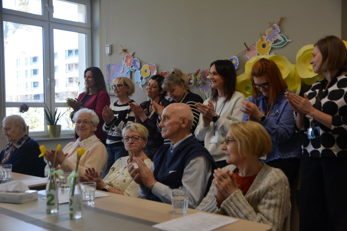 Na zdjęciu grupa osób w różnym wieku bijąca brawa