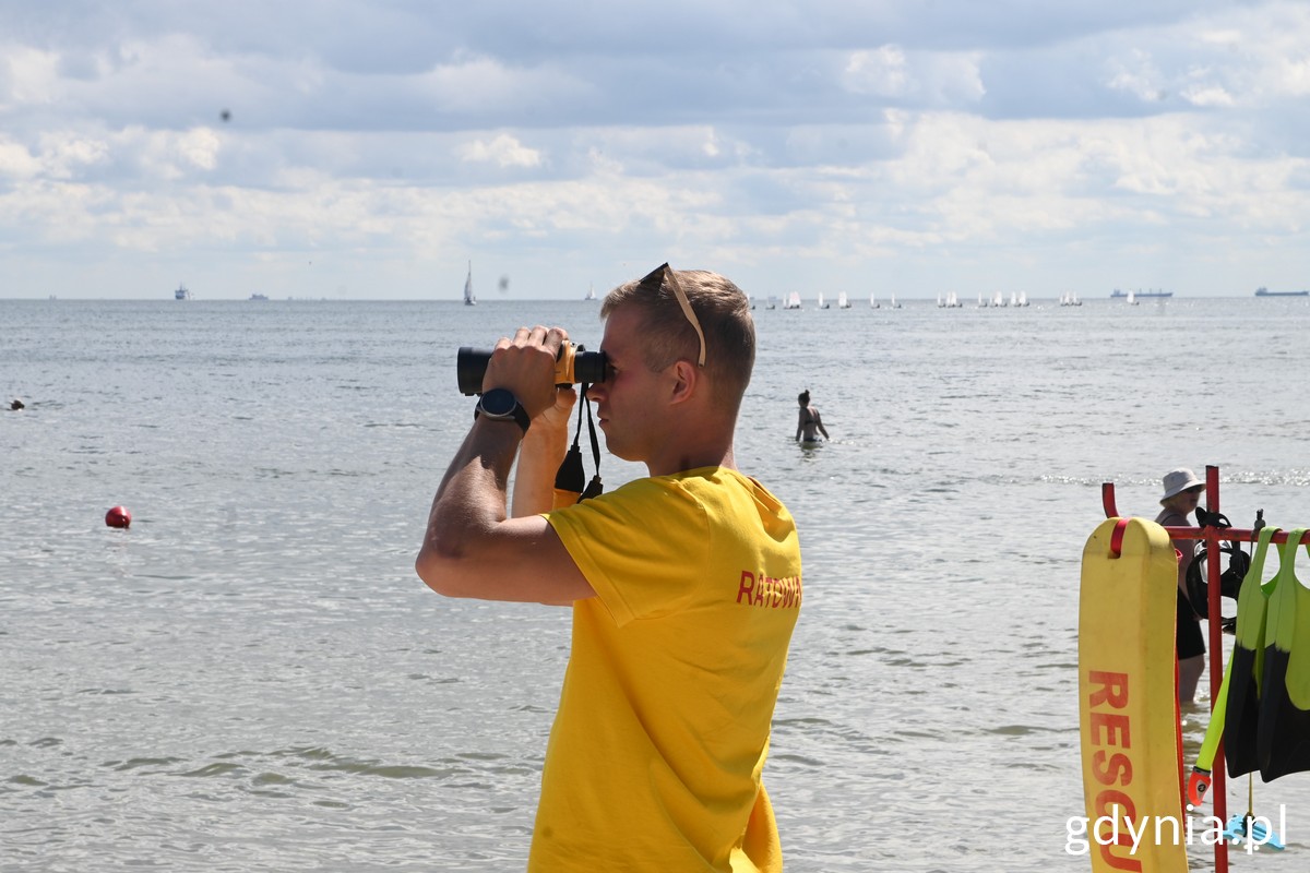 Ratownik na plaży Środmieście patrzy przez lornetkę w stronę morza