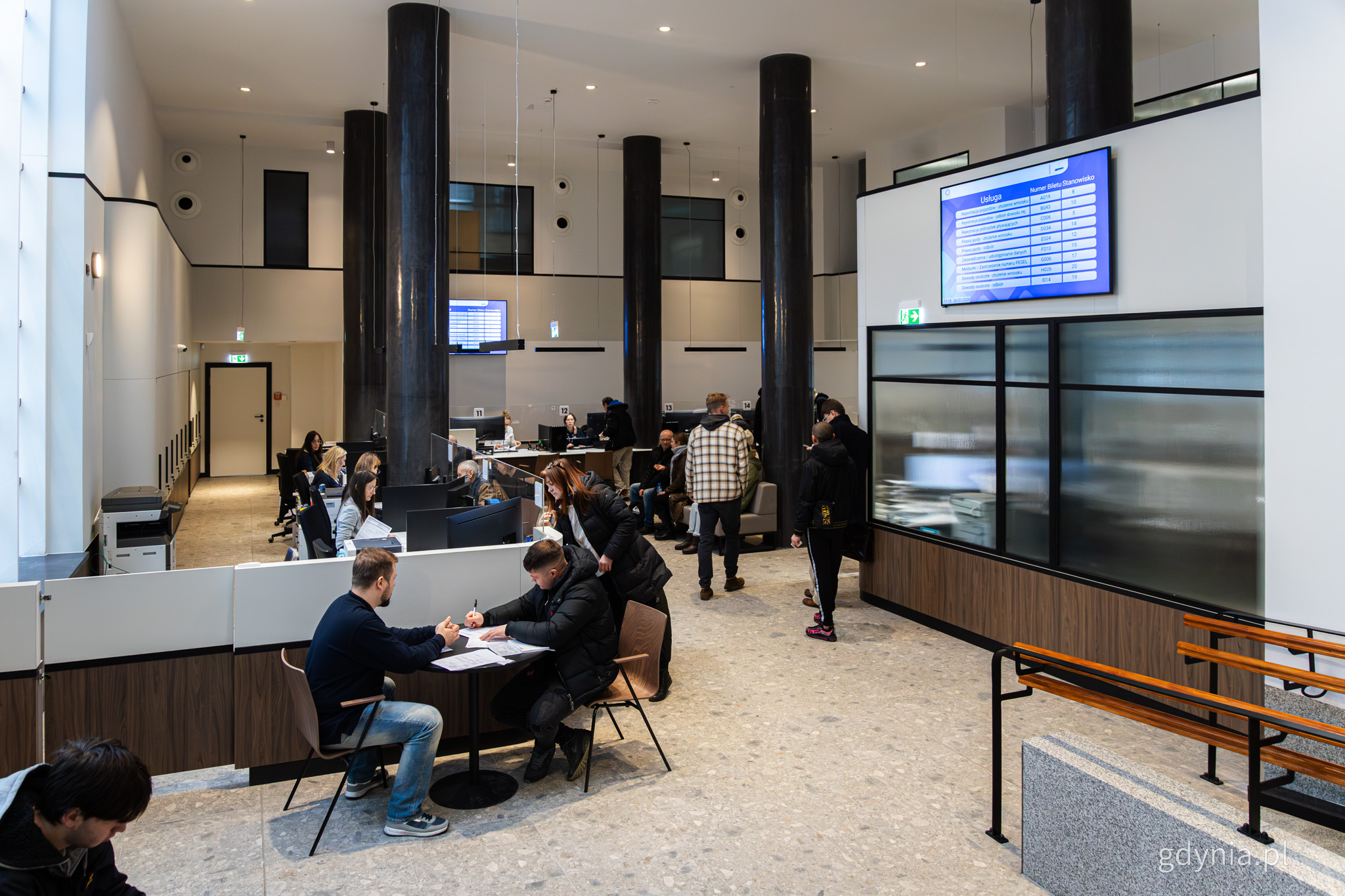 Sala obsługi w Urzędzie miasta, widoczne stanowiska, sofy, klienci i urzędnicy obsługujący klient&oacute;w