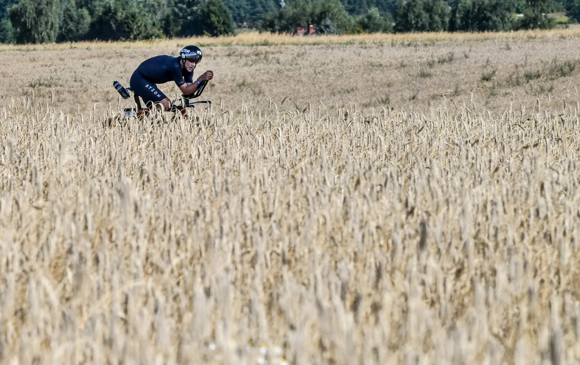 Na zdjęciu widzimy kolarza jadącego przez bezkresny, wiejski krajobraz