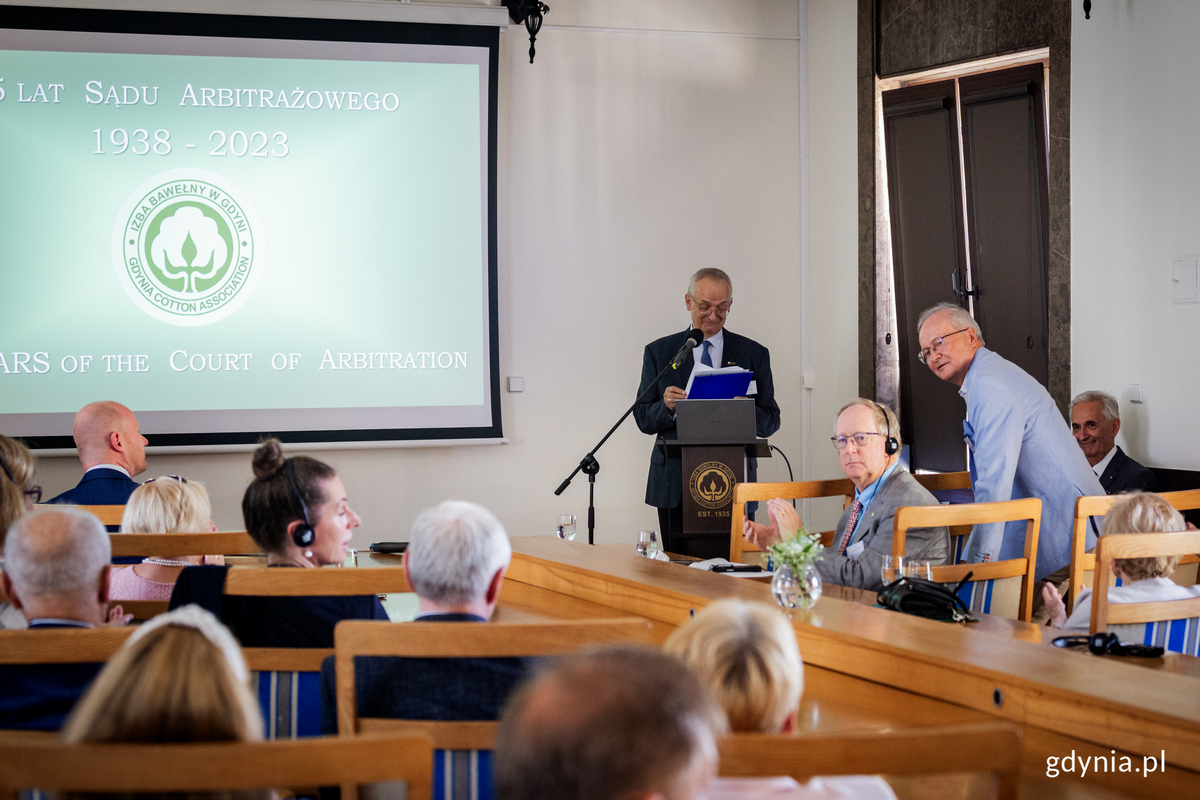 Męzczyzna przemawia na mównicy w sali konferencyjnej.