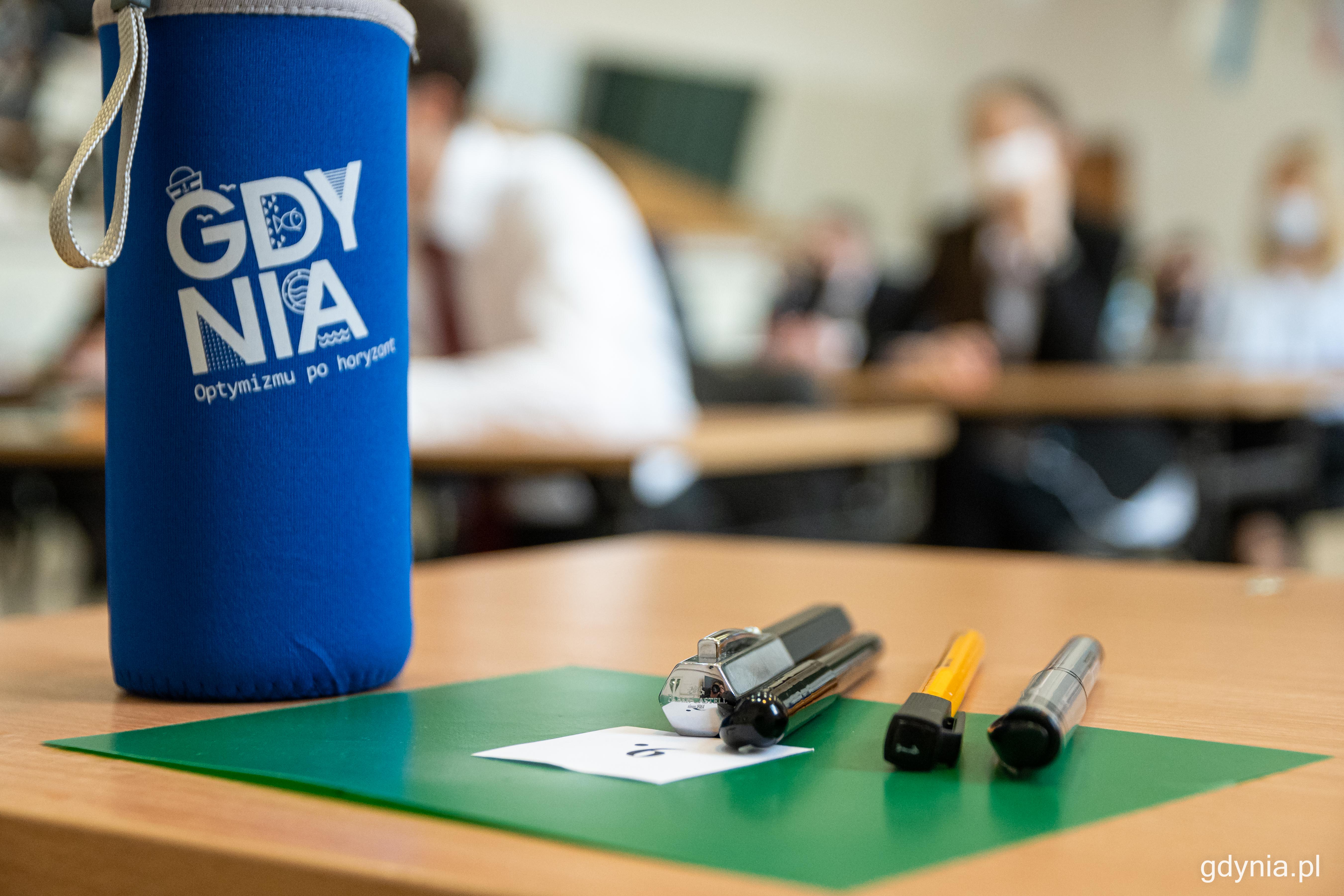 Szklane butelki wielokrotnego użytku dla gdyńskich maturzystów. Na materiałowym etui widnieje hasło „Optymizmu po horyzont”. Fot. Kamil Złoch