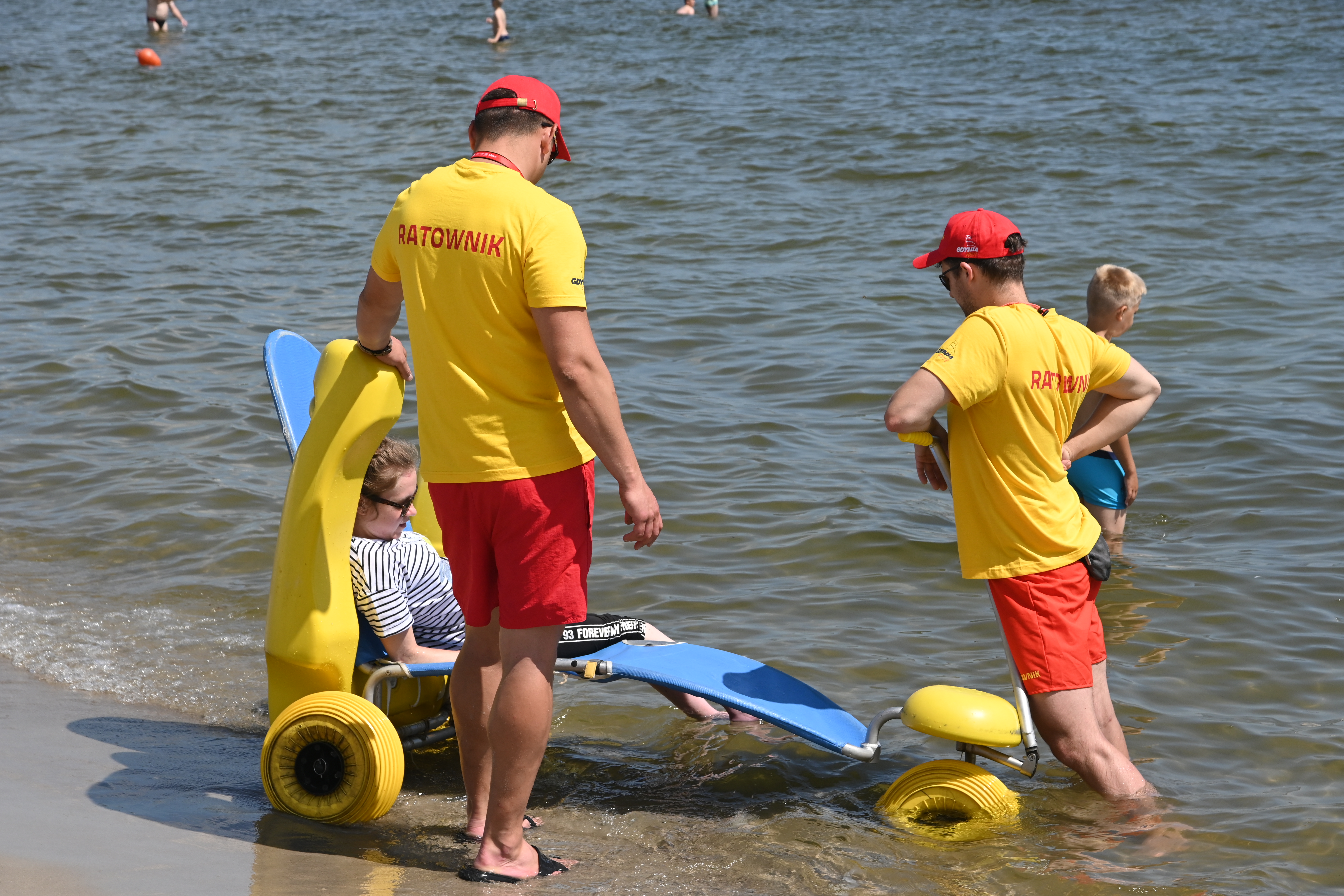 Ratownicy na plaży Śródmieście pomagają osobie z niepełnosprawnością zażyć kąpieli morskiej. Fot. Magdalena Śliżewska