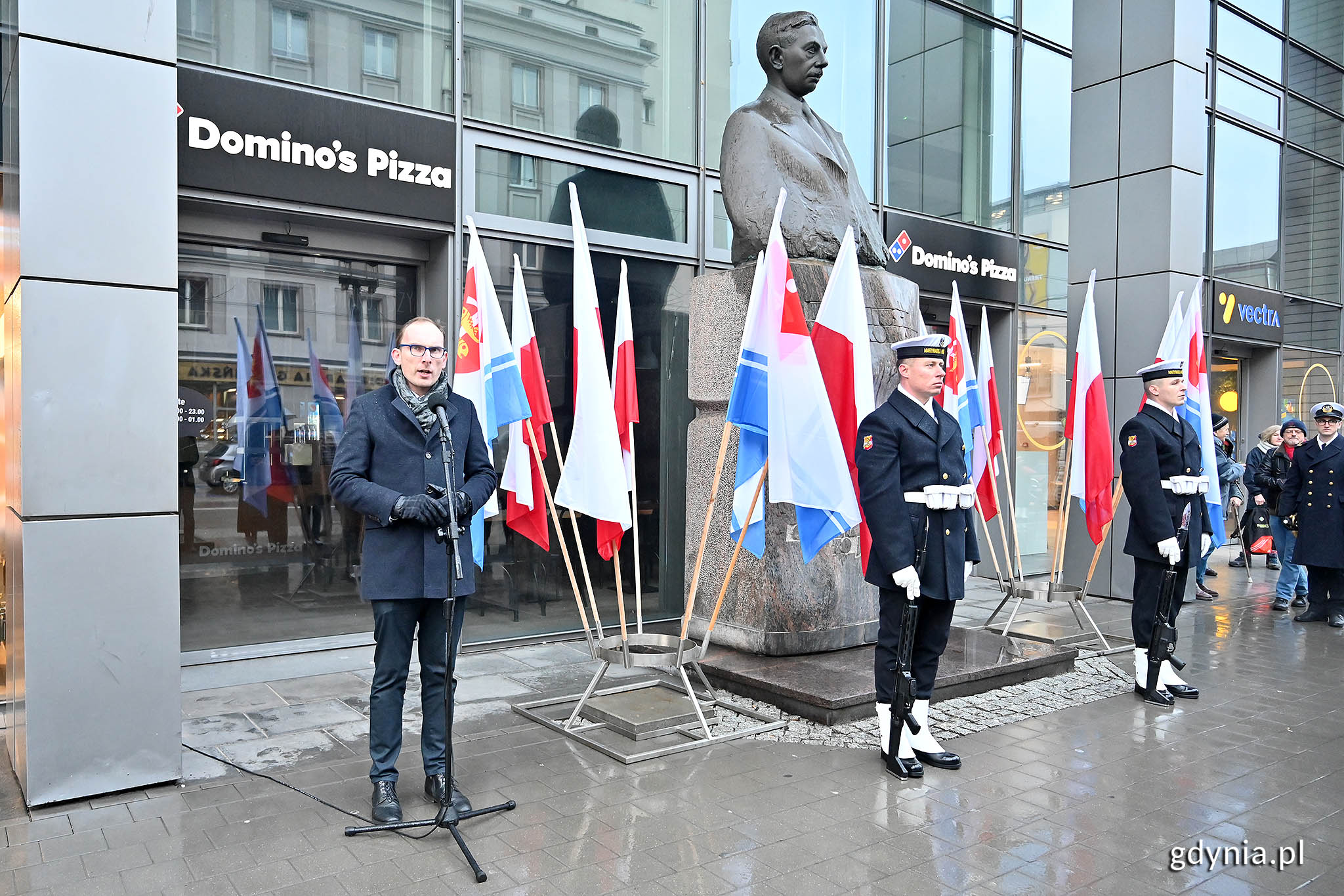 Mężczyzna przemawia pod pomnikiem.