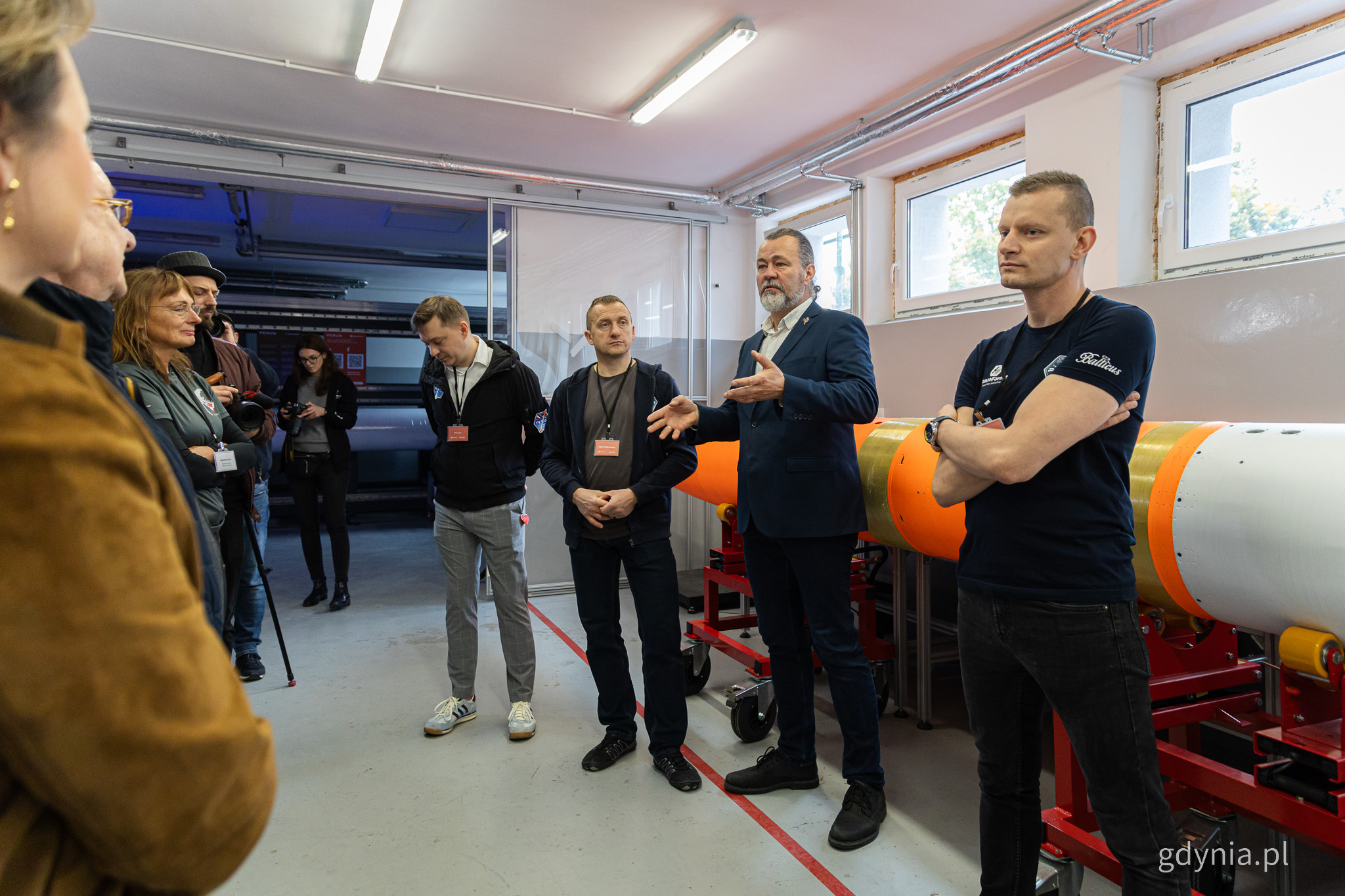 Hala warsztatowa, rakieta PERUN, kilka osób przemawia na środku