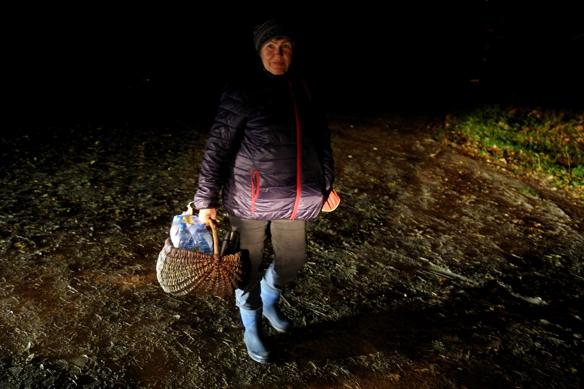 Pani Krystyna ze wsi koło Hajnówki dowiedziała się o odnalezieniu w lesie przez wolontariuszy kolejnych uchodźców z Syrii. Przyniosła w koszu wodę, ciepłą herbatę w termosie i zupę w słoiku. 23 października 2021. Fot. Przemysław Kozłowski / Testigo Documentary