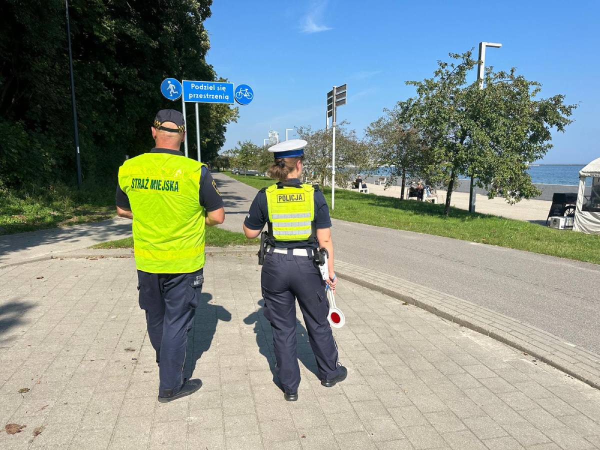 Strażnik miejski i policjantka patrolujący drogę dla rowerów