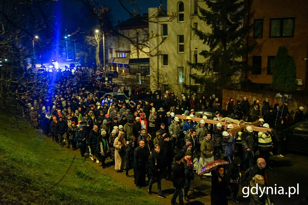 Ludzie idą w drodze krzyżowej ulicami miasta.