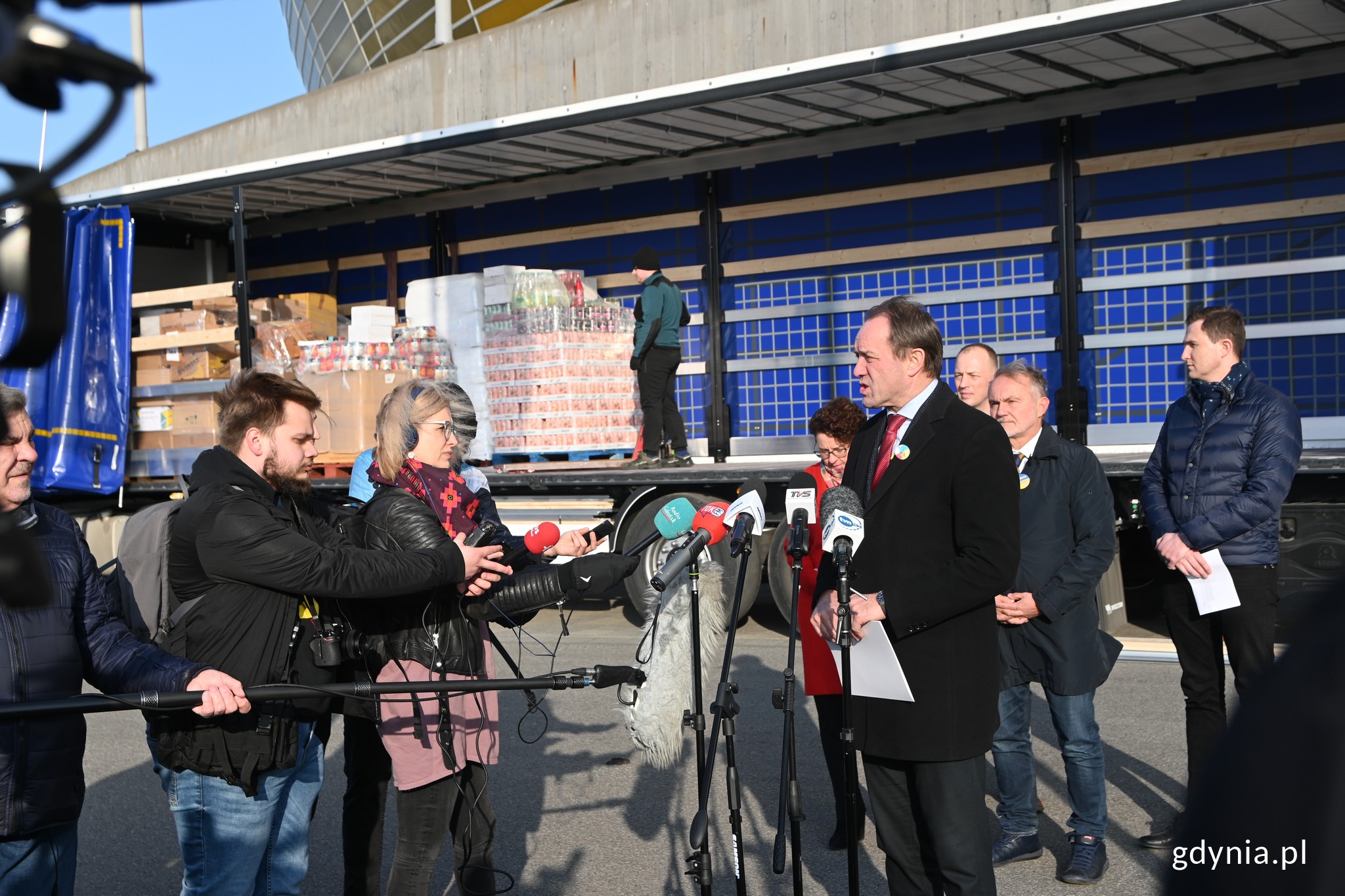 Konferencja prasowa przed stadionem w Gdańsku. Przemawia Mieczysław Struk - marszałek województwa pomorskiego. Za nim stoją (od lewej): Magdalena Czarzyńska-Jachim - wiceprezydent Sopotu, Wojciech Szczurek - prezydent Gdyni i Piotr Grzelak - zastępca prezydenta Gdańska. W tle tir z pakunkami dla Ukrainy // fot. Magdalena Czernek