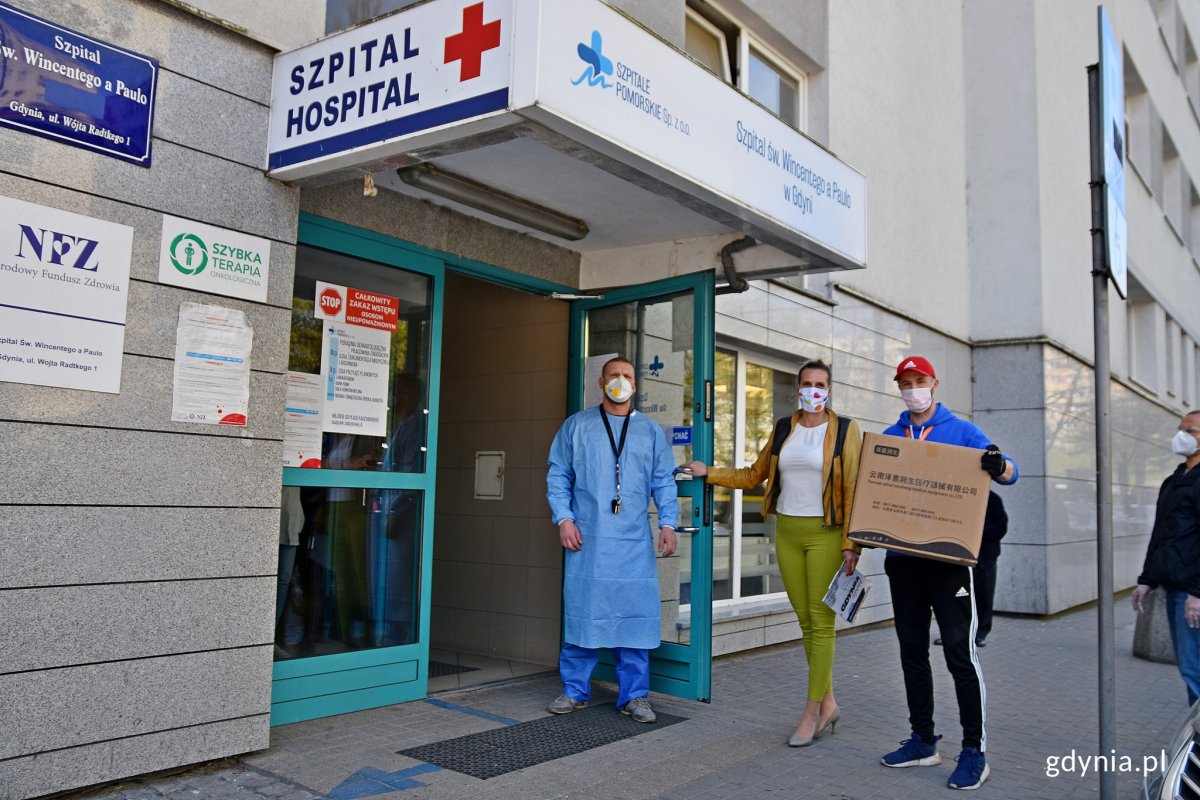 Lekarz w niebieskim fartuchu przed wejściem do szpitala św. Wincentego a Paulo w Gdyni. Odbiera transport maseczek ochronnych od miasta // fot. Paweł Kukla