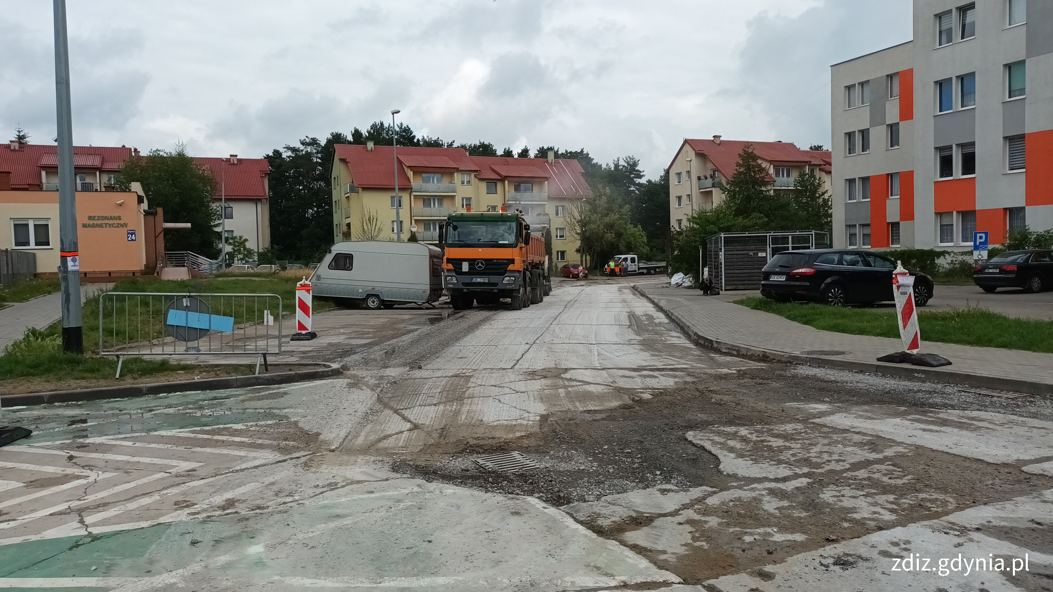 spękana nawierzchnia, trwające prace drogowe, w tle budynki