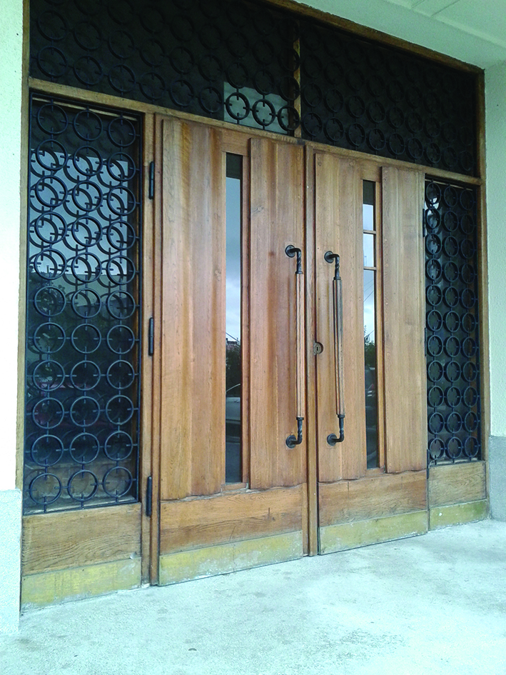 Wejście główne do budynku Wydziału Nawigacyjnego Uniwersytetu Morskiego przy al. Jana Pawła II 3, z drzwiami z motywem dekoracyjnej fali na powierzchni.  