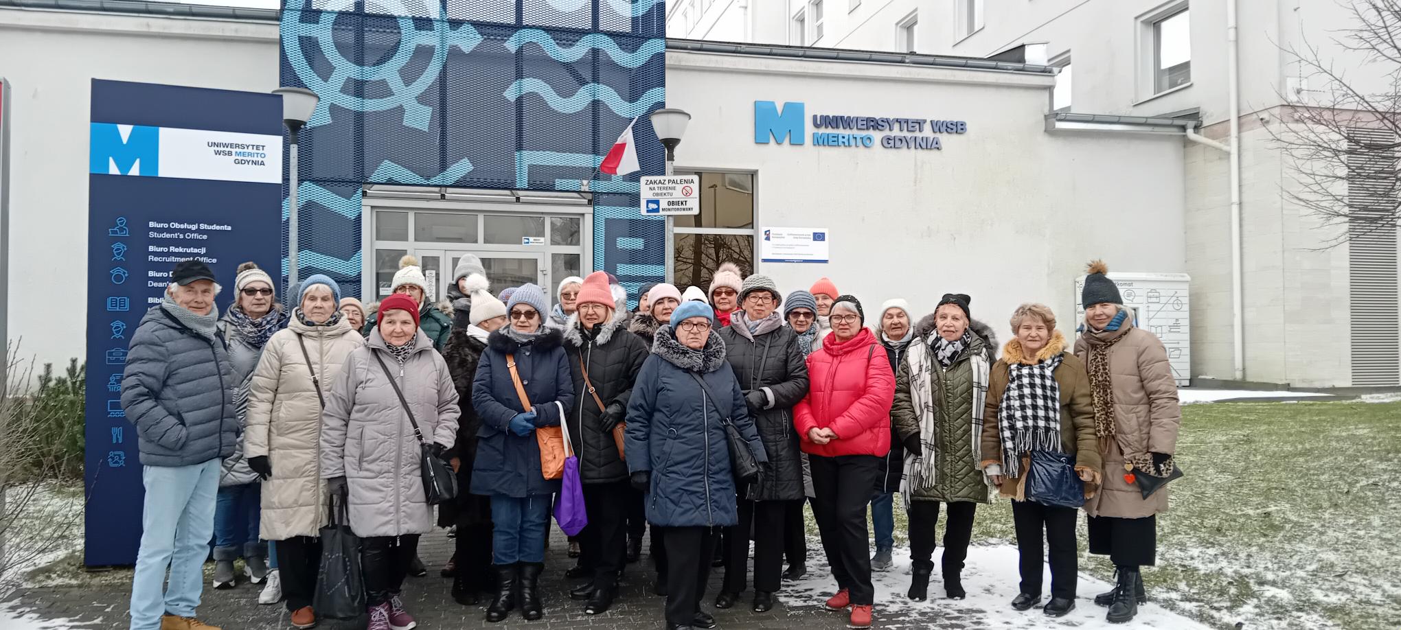 Seniorzy po wykładzie Jacka Winiarskiego&nbsp;pt.&nbsp;&bdquo;Elementy składowe miłości&rdquo; przed budynkiem WSB Merito Gdynia