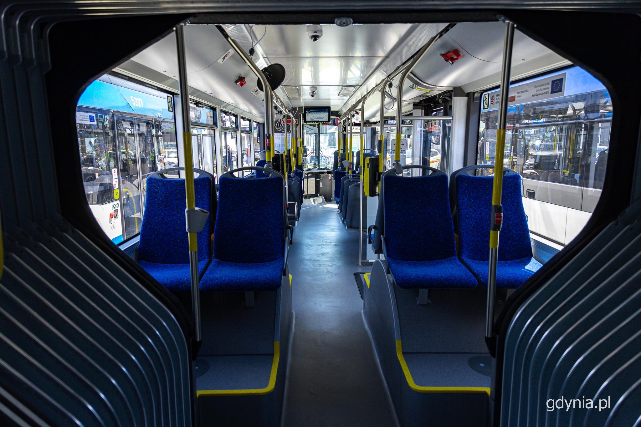 Wnętrze przegubowego autobusu, niebieskie fotele