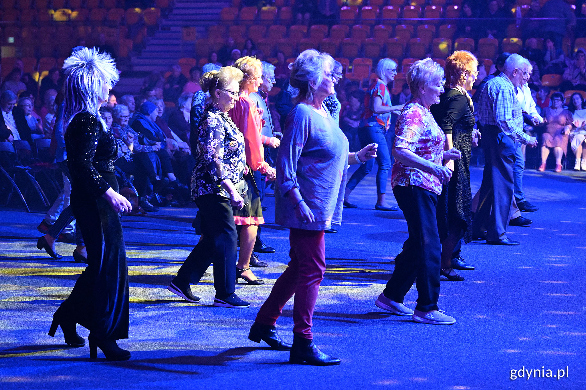 Parkiet hali w Gdyni, przyciemnione światła, grupa senior&oacute;w tańczy