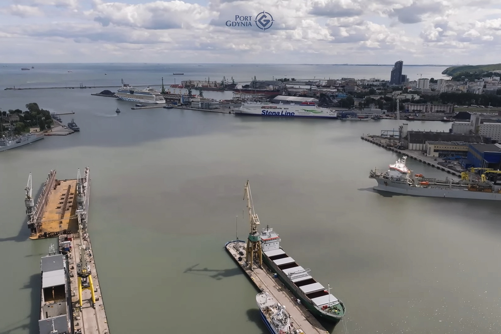 Widok z lotu ptaka na port, w kt&oacute;rym widać statki zacumowane przy nabrzeżach i dokach.