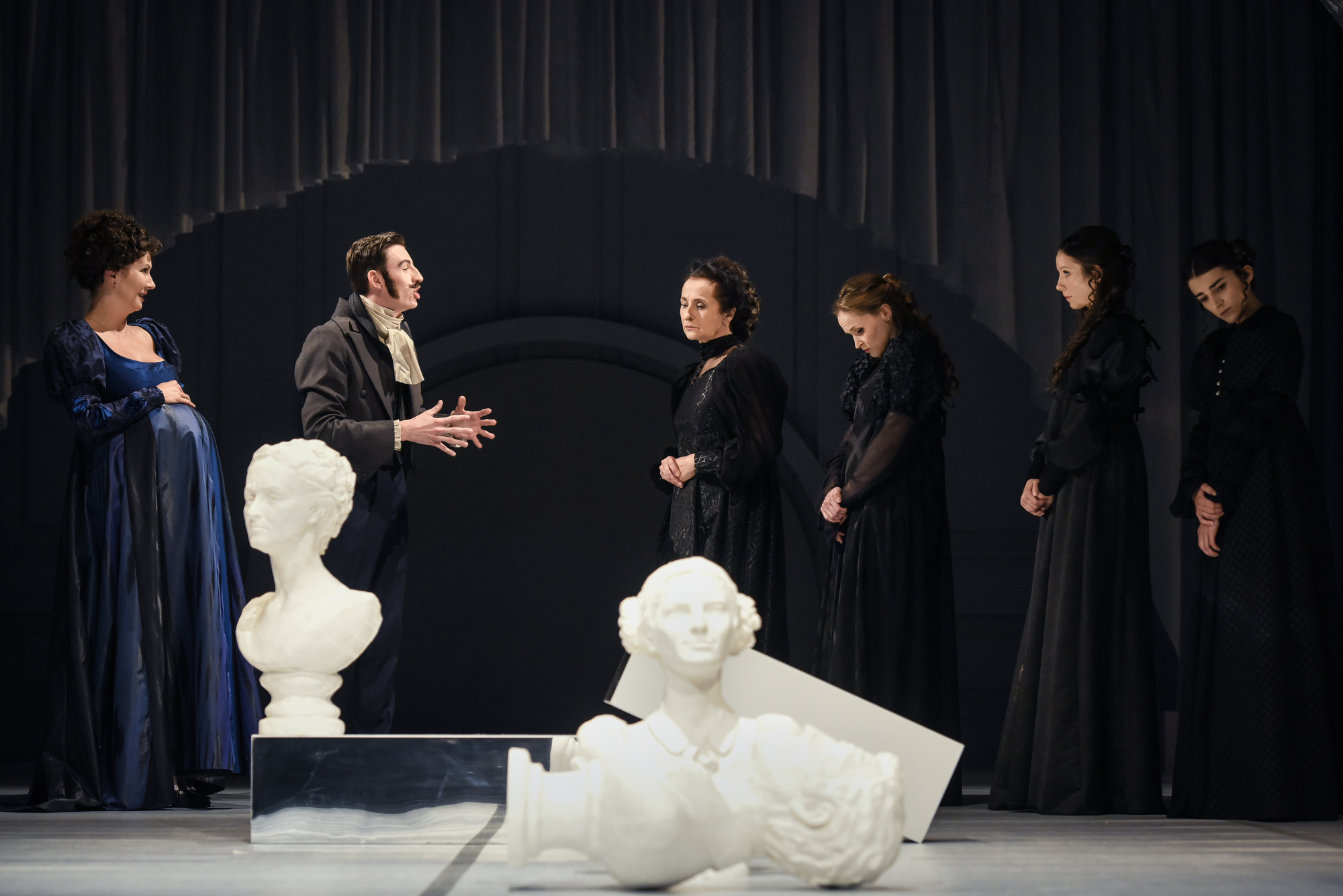 Zdjęcie z pr&oacute;by medialnej "Rozważnej i romantycznej" w Teatrze Miejskim w Gdyni. Na pierwszym planie rzeźby rodowe, z tyłu aktorzy wcielający się w rodzinę Dashwood&oacute;w i ich krewnych // fot. Roman Jocher
