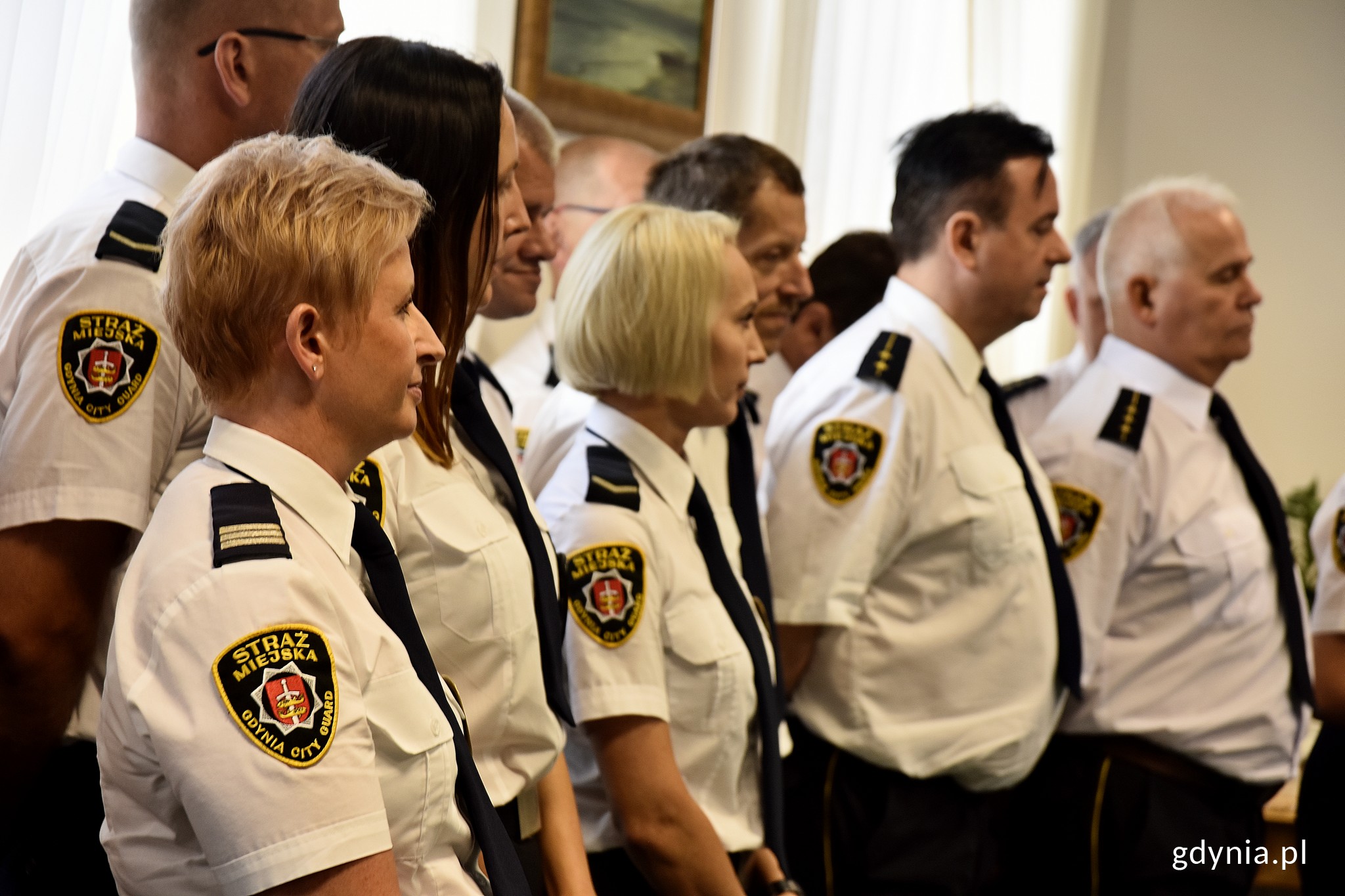 Na zdjęciu znajdują się strażnicy miejscy, kt&oacute;rzy czekają na odbi&oacute;r podziękowań za swoją pracę