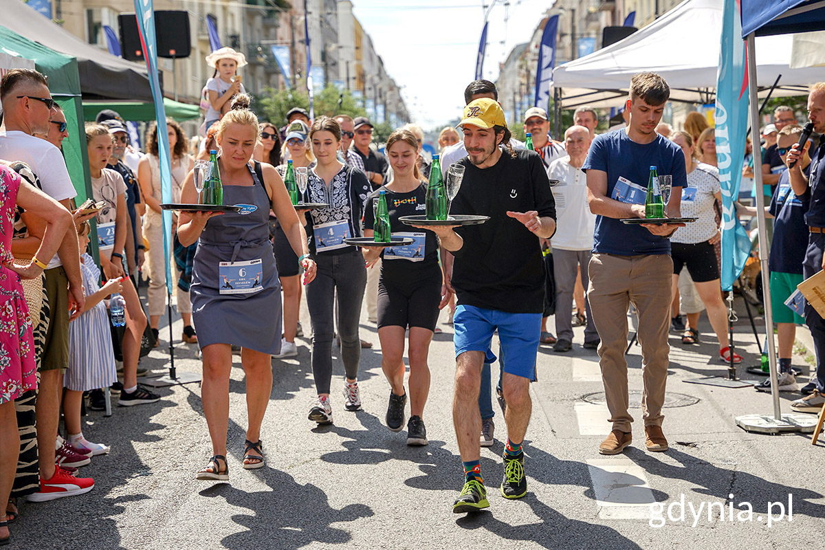 Kelnerzy z tacami przygotowani do biegu ul. Świętojańską