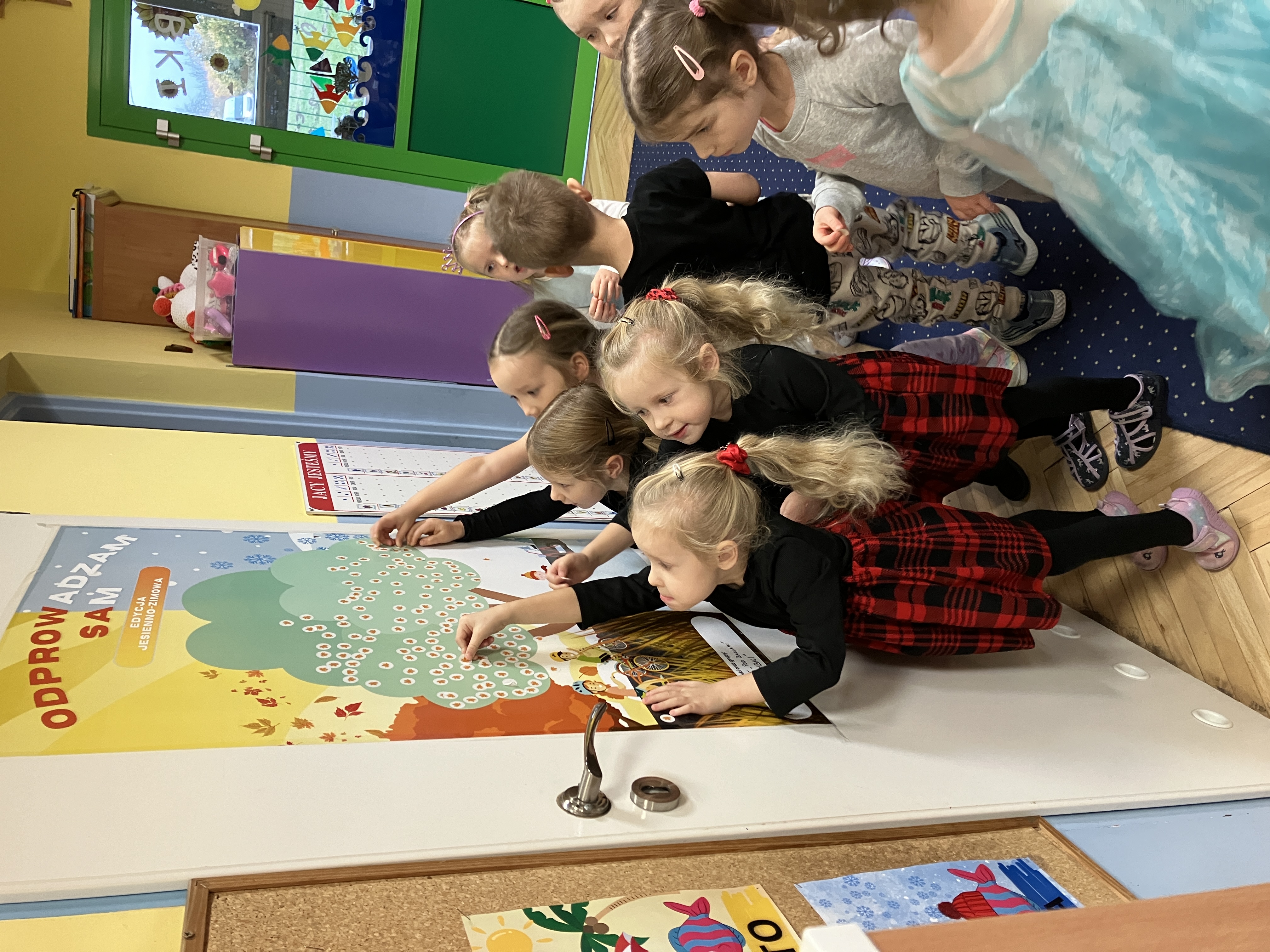 Przedszkole "Pod żaglami " nr 35 w Gdyni, dzieci podczas naklejania naklejek na drzewko edukacyjne 